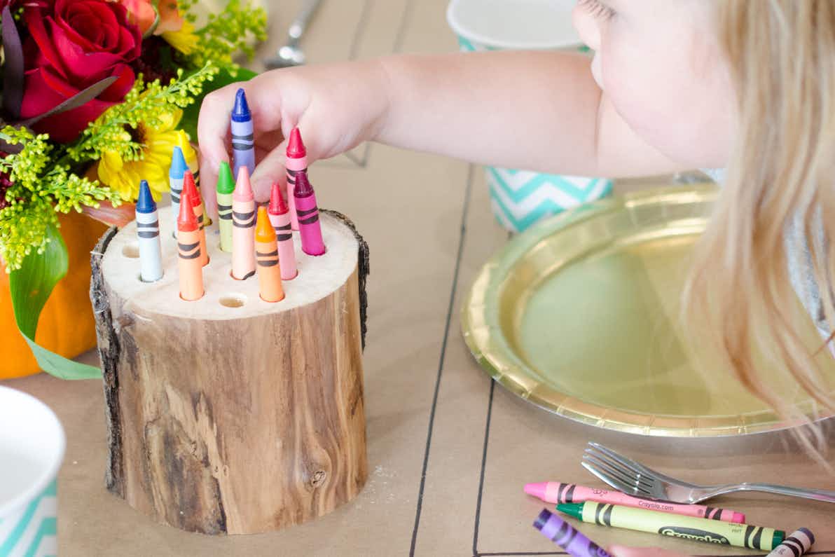 A child pulling a crayon out of a log crayon holder