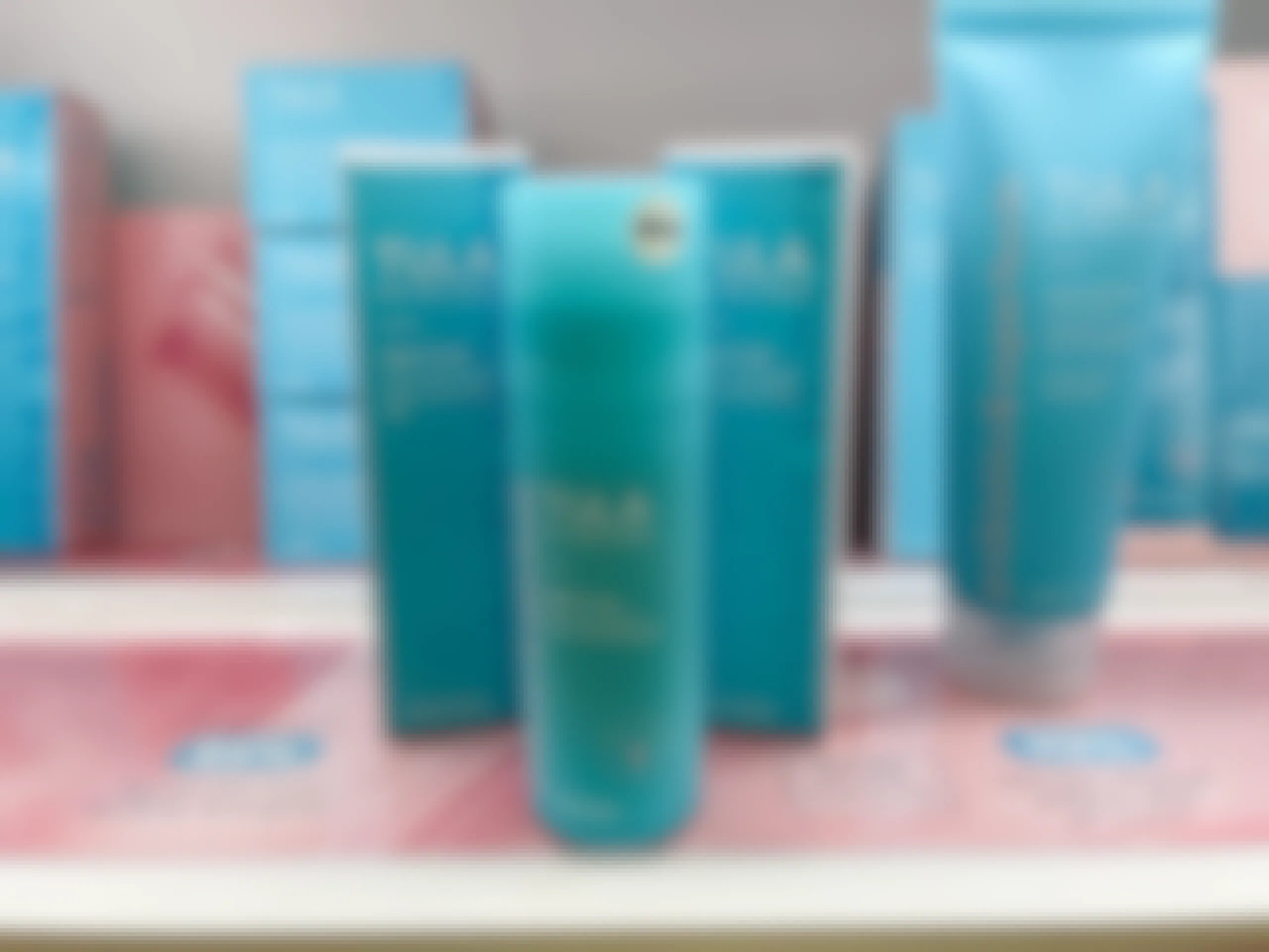 A bottle of Tula skincare clear it up acne clearing and tone correcting gel sitting on a store shelf with two boxes of Tula skincare clear it up acne clearing and tone correct in gel behind it.