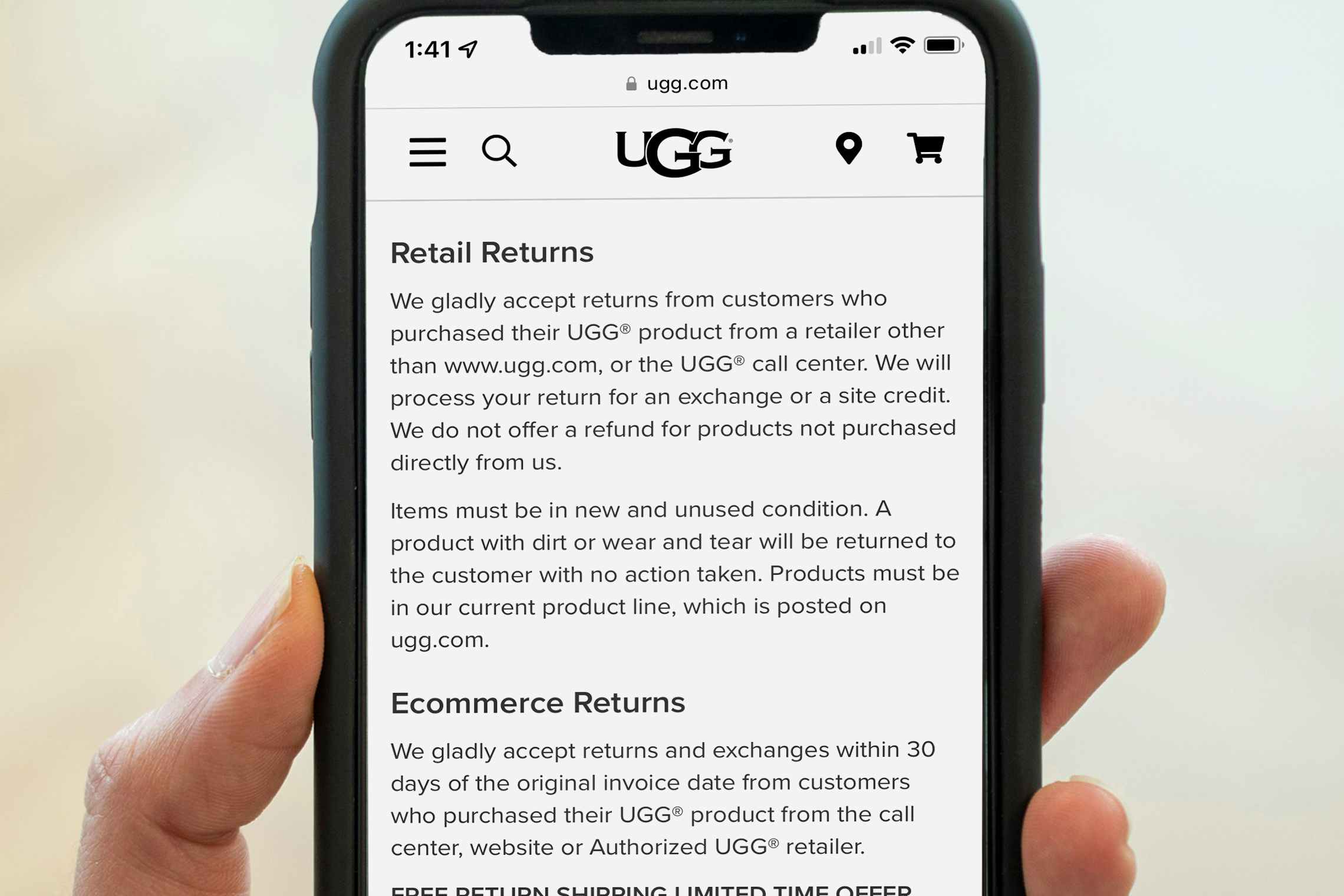 A person's hand holding up a phone displaying the UGG return policy on their website.