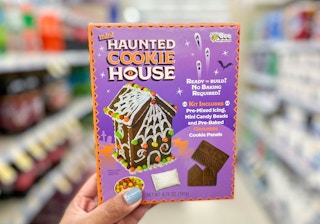 hand holding mini haunted cookie house in aisle