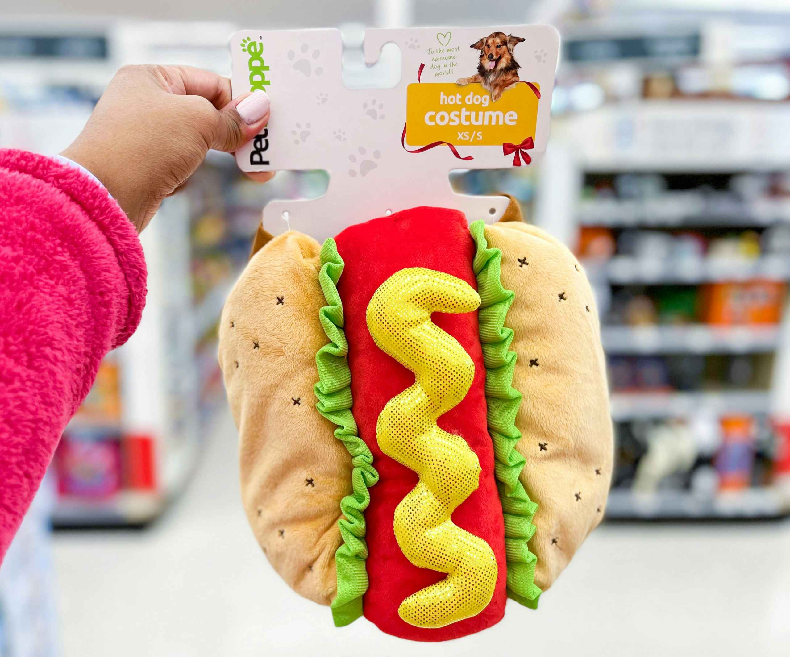 hand holding Petshoppe hotdog costume in aisle
