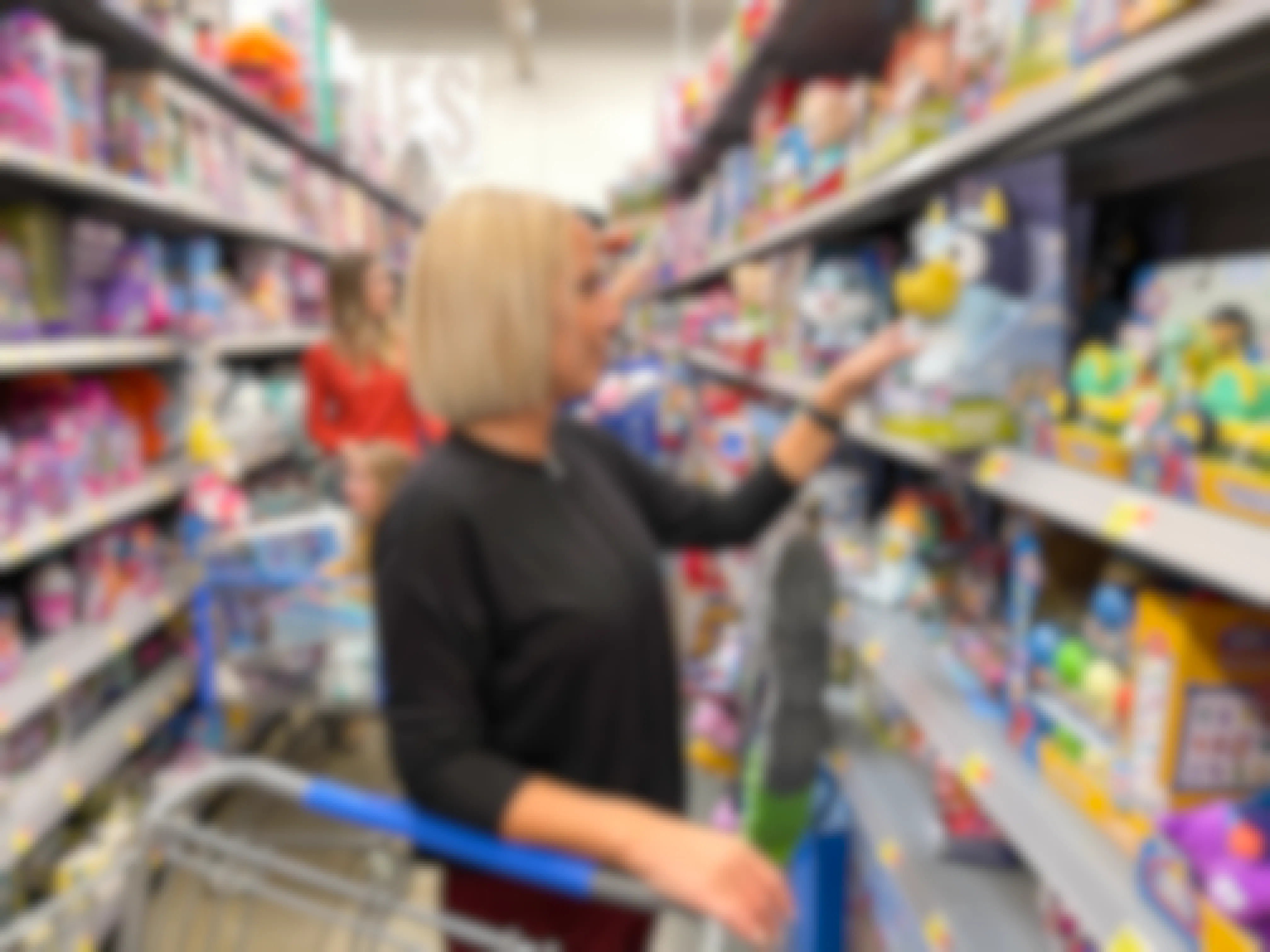 A woman looking at a Toy on a Walmart toy aisle.