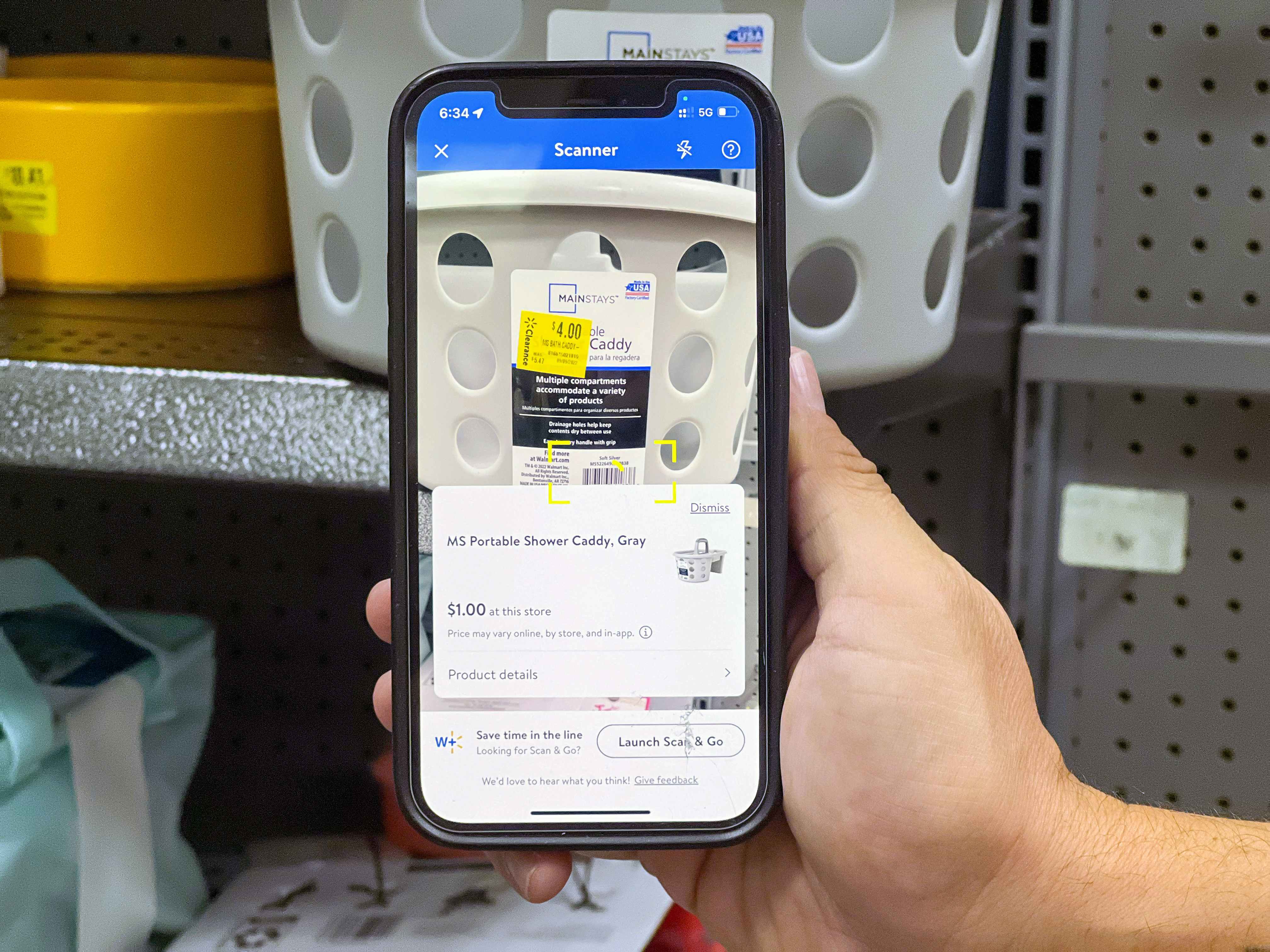 Someone holding a phone, scanning a clearance item in the Walmart app which shows that although the sticker says the item is $4, it is actually only $1
