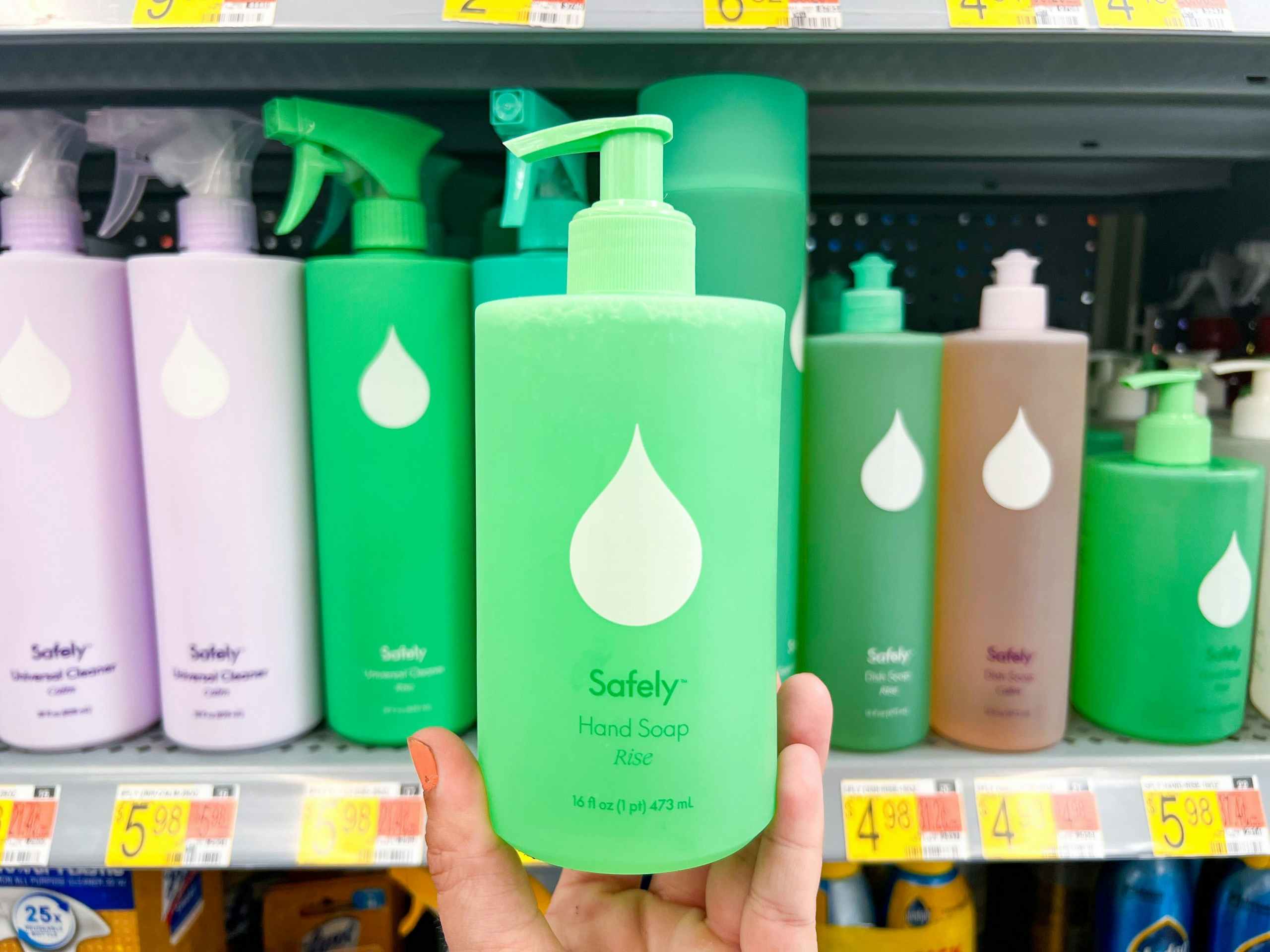 hand holding a bottle of Safely hand soap in front of a Walmart shelf with like items