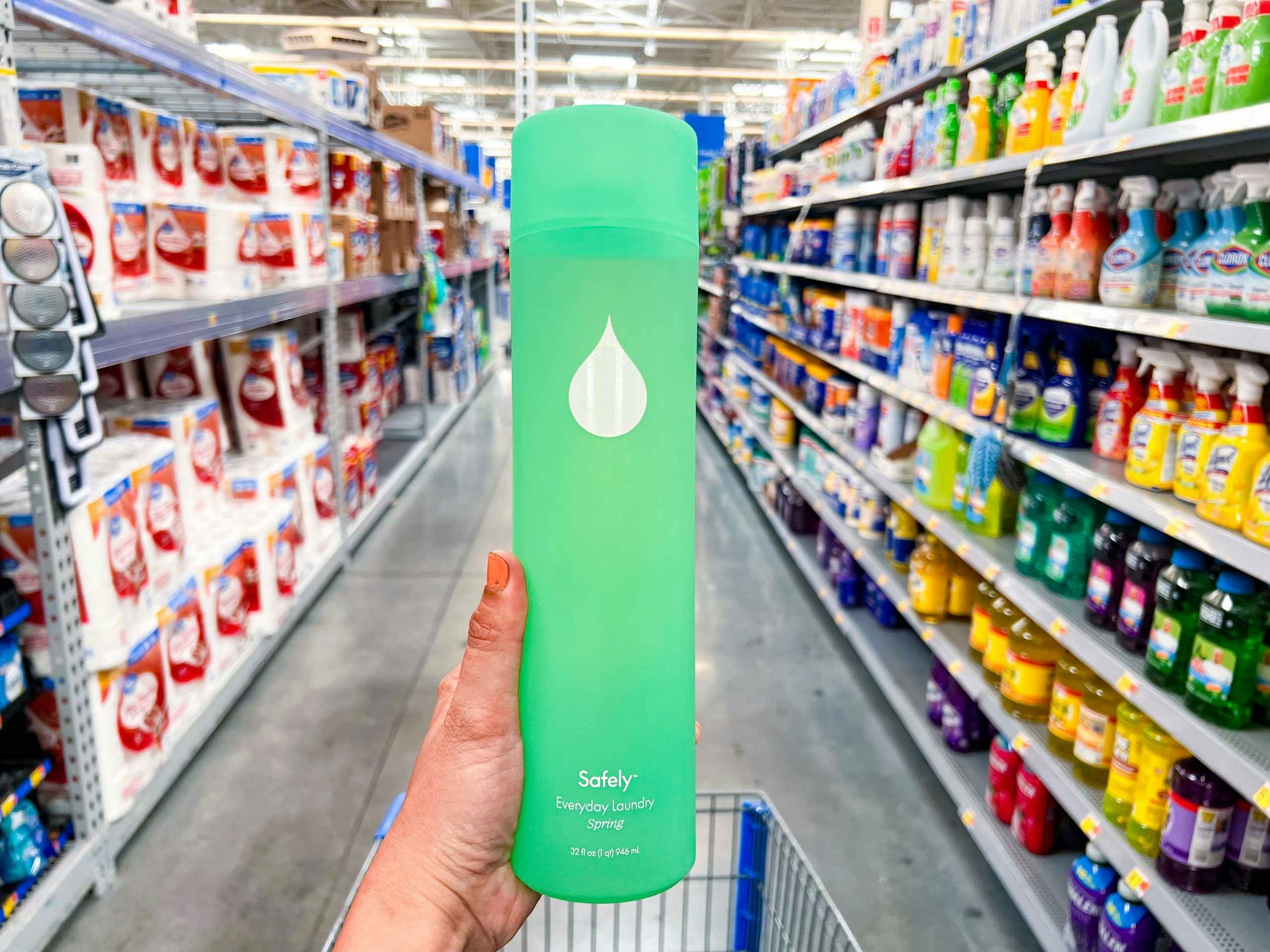 a hand holding a bottle of Safely laundry detergent in a Walmart aisle