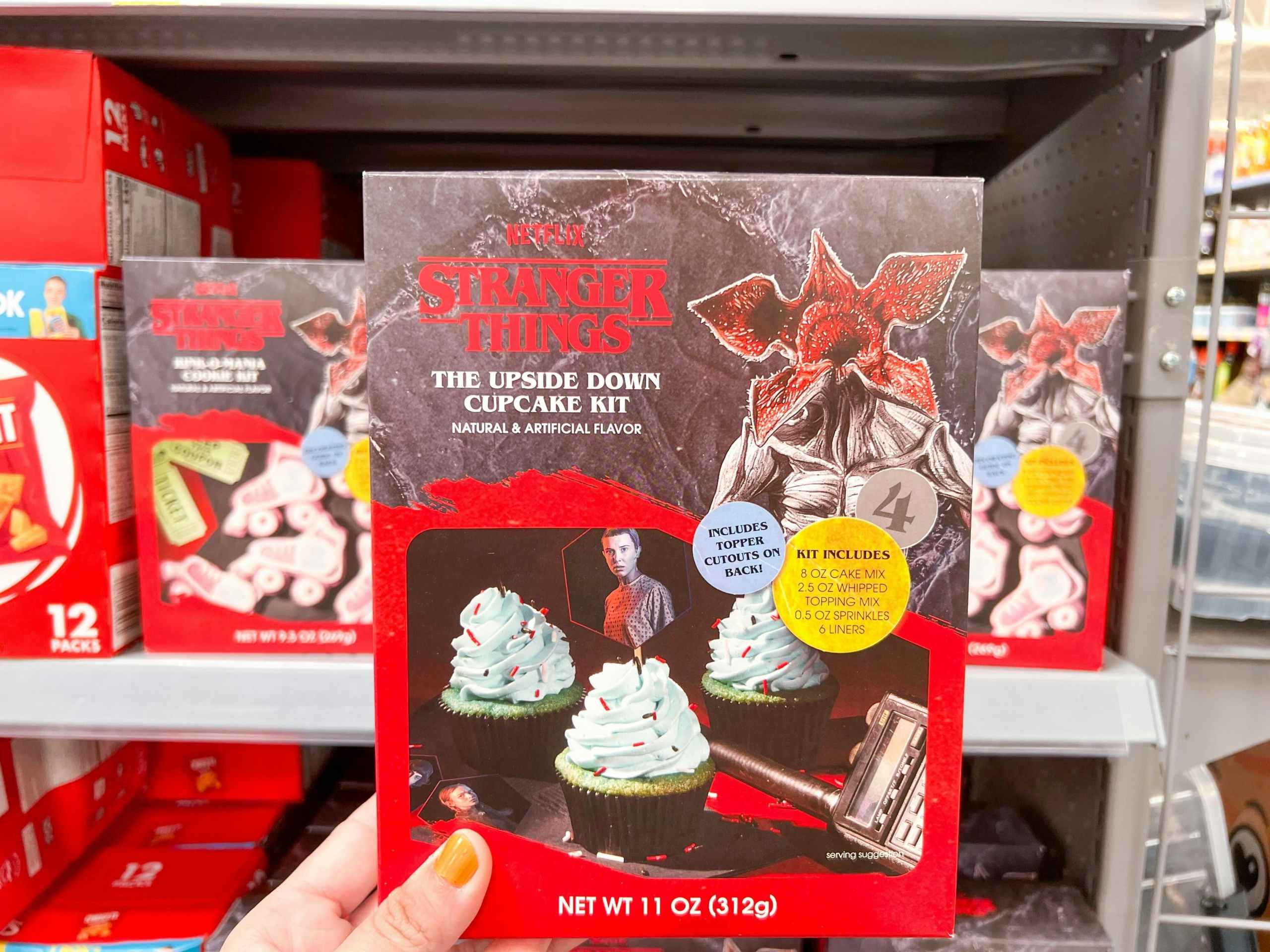 Stranger Things Upside Down cupcakes held by hand in front of other cookie sets