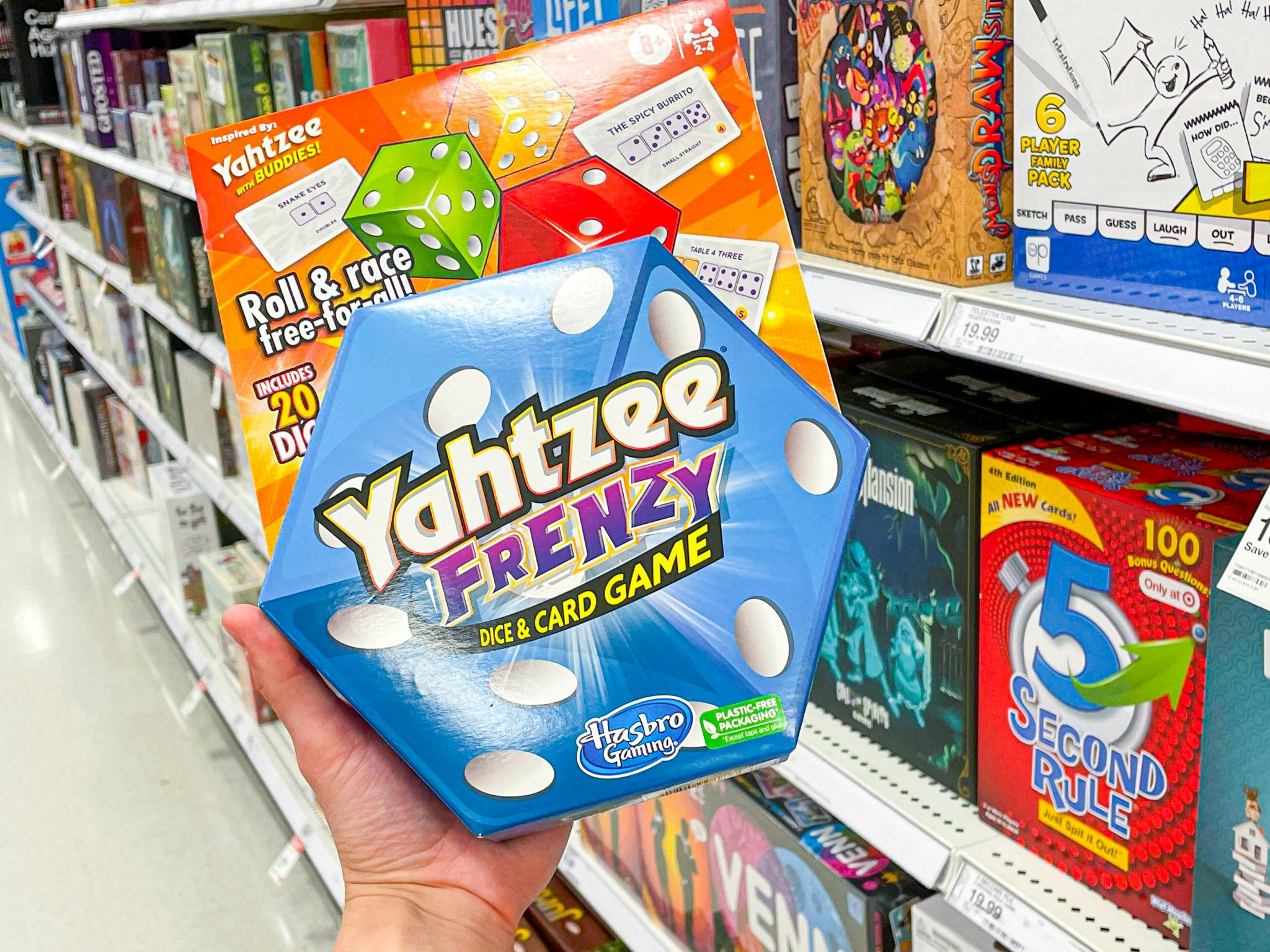 A person's hand holding a Yahtzee Frenzy card game in target aisle
