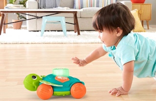 A boy chasing after a Fisher-Price turtle.