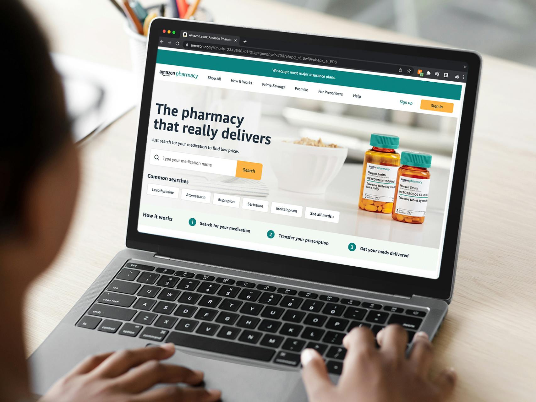 A person looking at the Amazon Pharmacy landing page on a laptop.