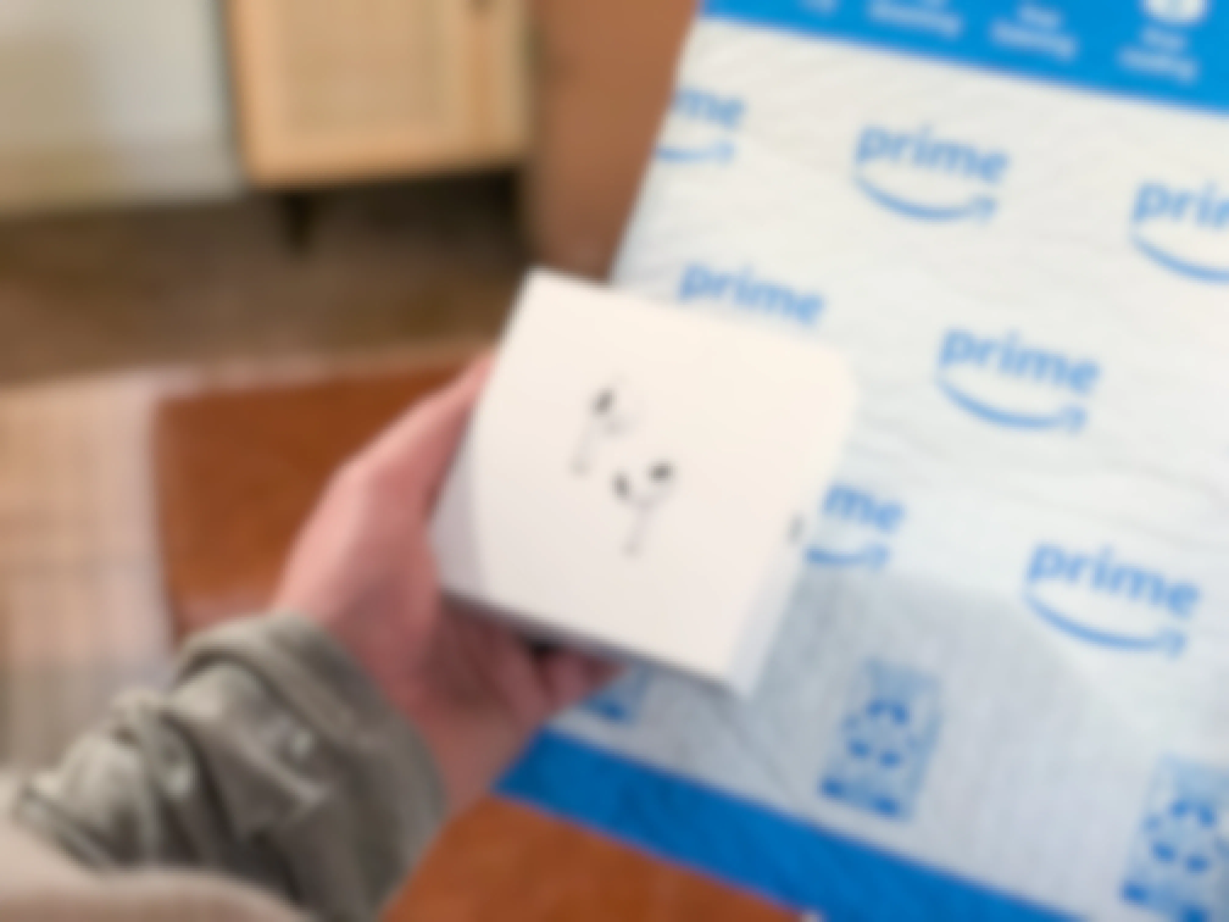 person holding apple airpods box with amazon package