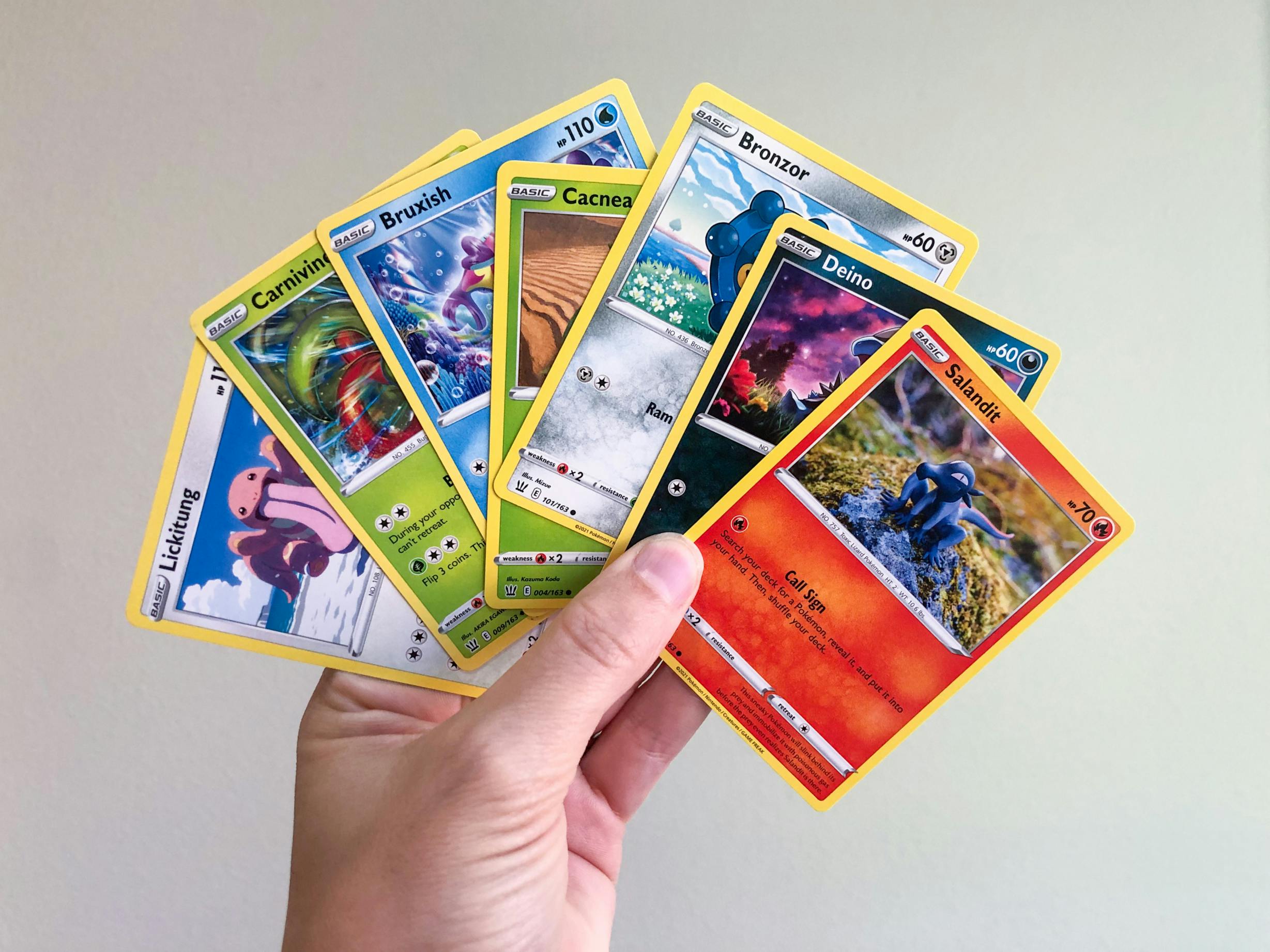 hand holding variety of pokemon cards