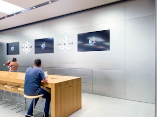 a person sitting down at the apple genius bar in the apple store