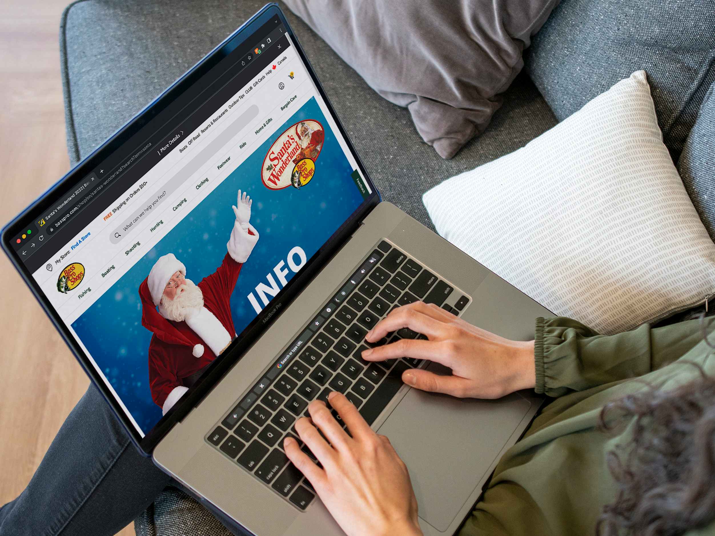 A person using a laptop to look at the Bass Pro Shops website page about Santa's Wonderland
