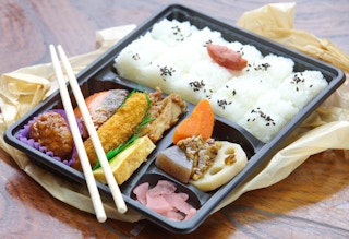 A bento box lunch sitting on a table with chopsticks