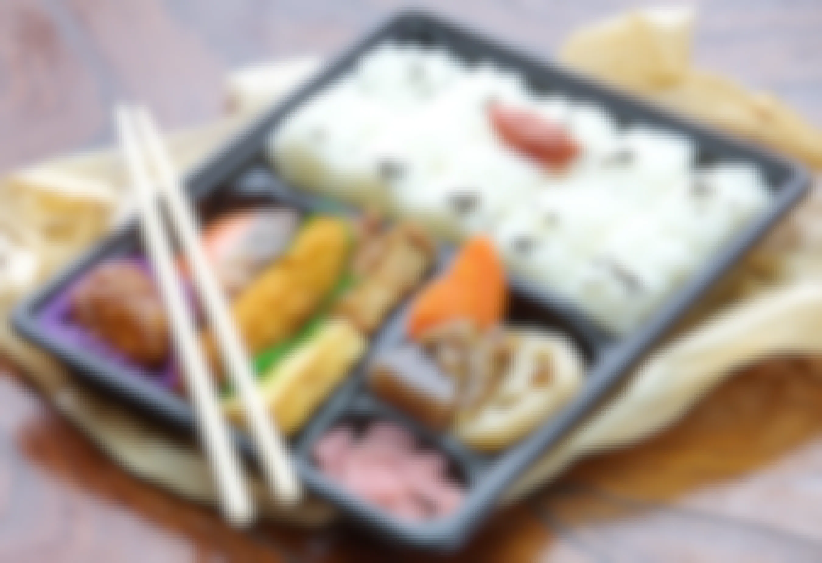 A bento box lunch sitting on a table with chopsticks