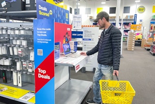 a person looking at a laptop by a top deals sign in best buy