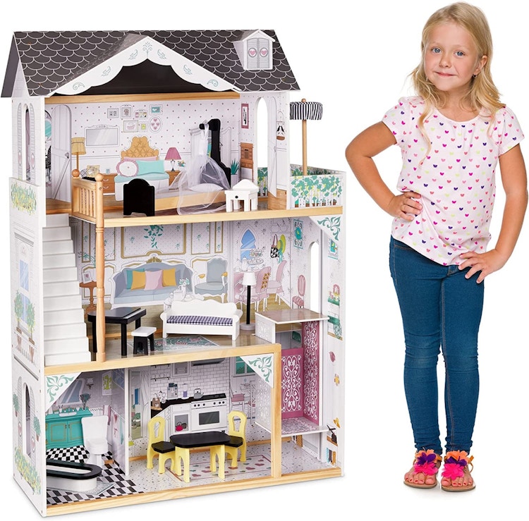 A child standing next to a Lil' Jumbl Kids Wooden Dollhouse