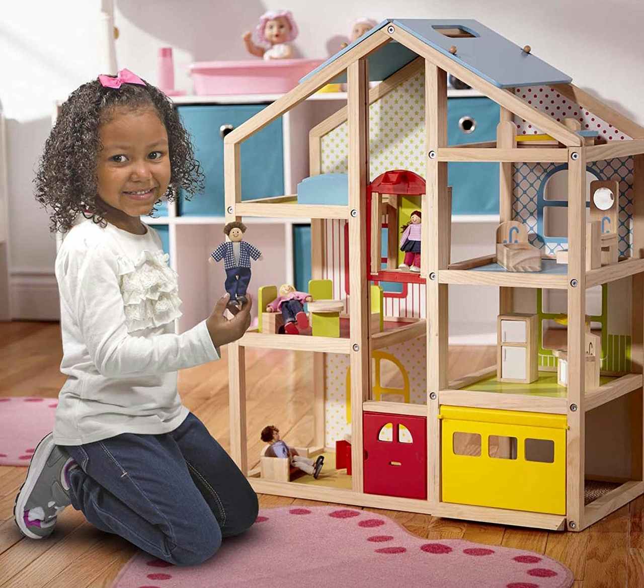A child playing with a Melissa & Doug Hi-Rise Wooden Dollhouse