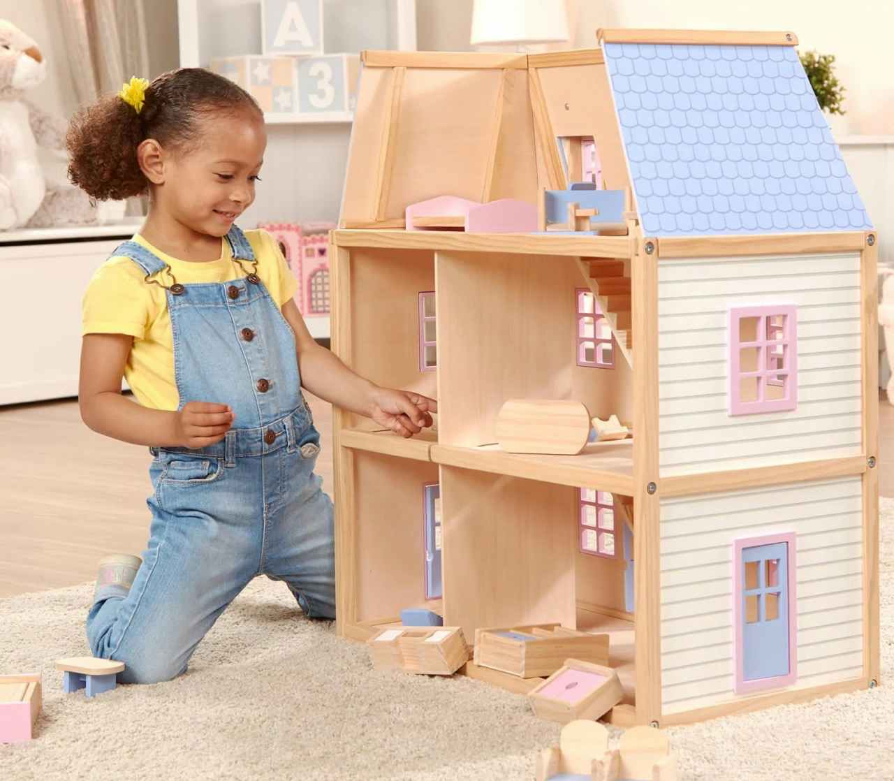 A child playing with a Melissa & Doug Multi-Level Dollhouse