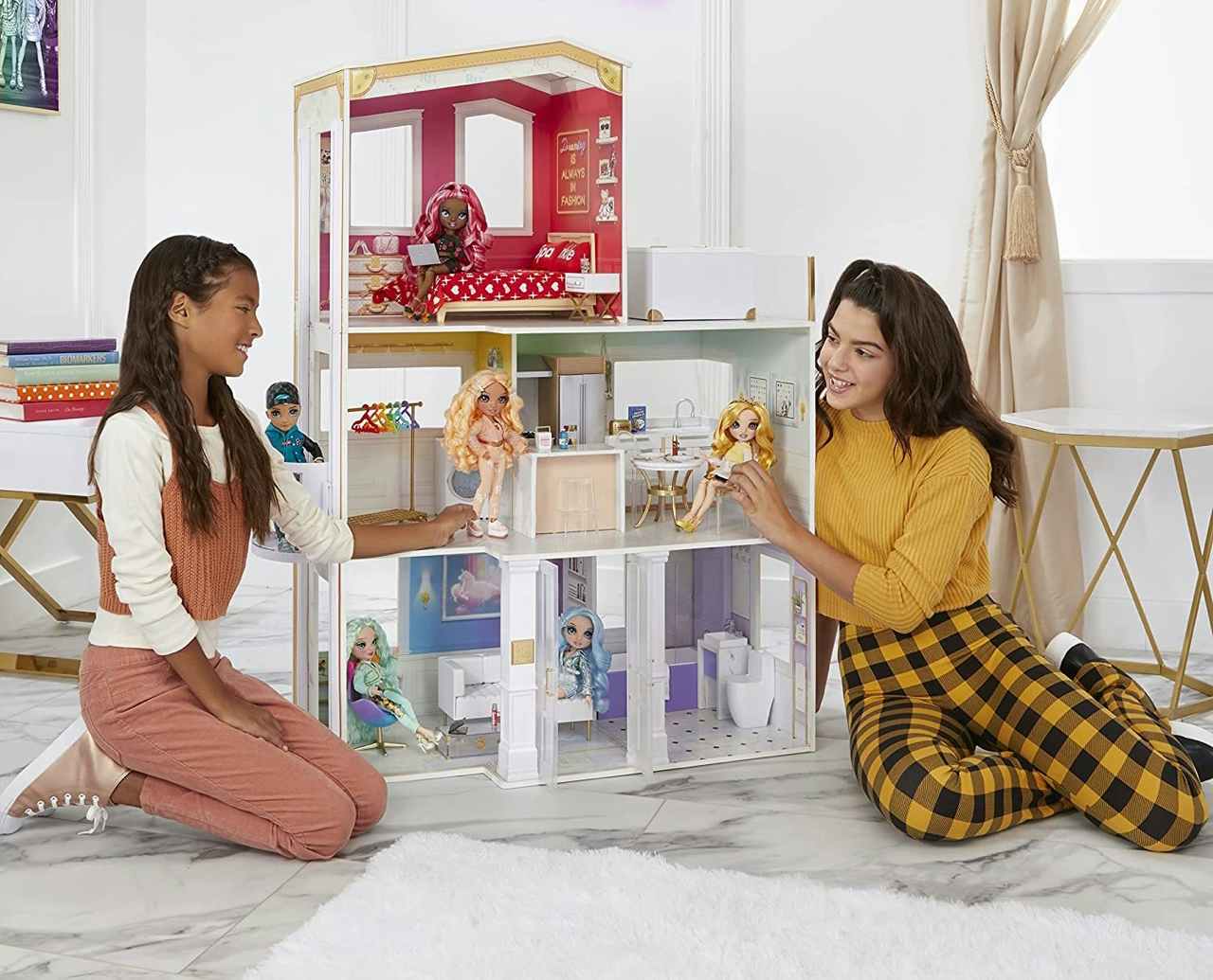 Two kids playing with a Rainbow High House dollhouse