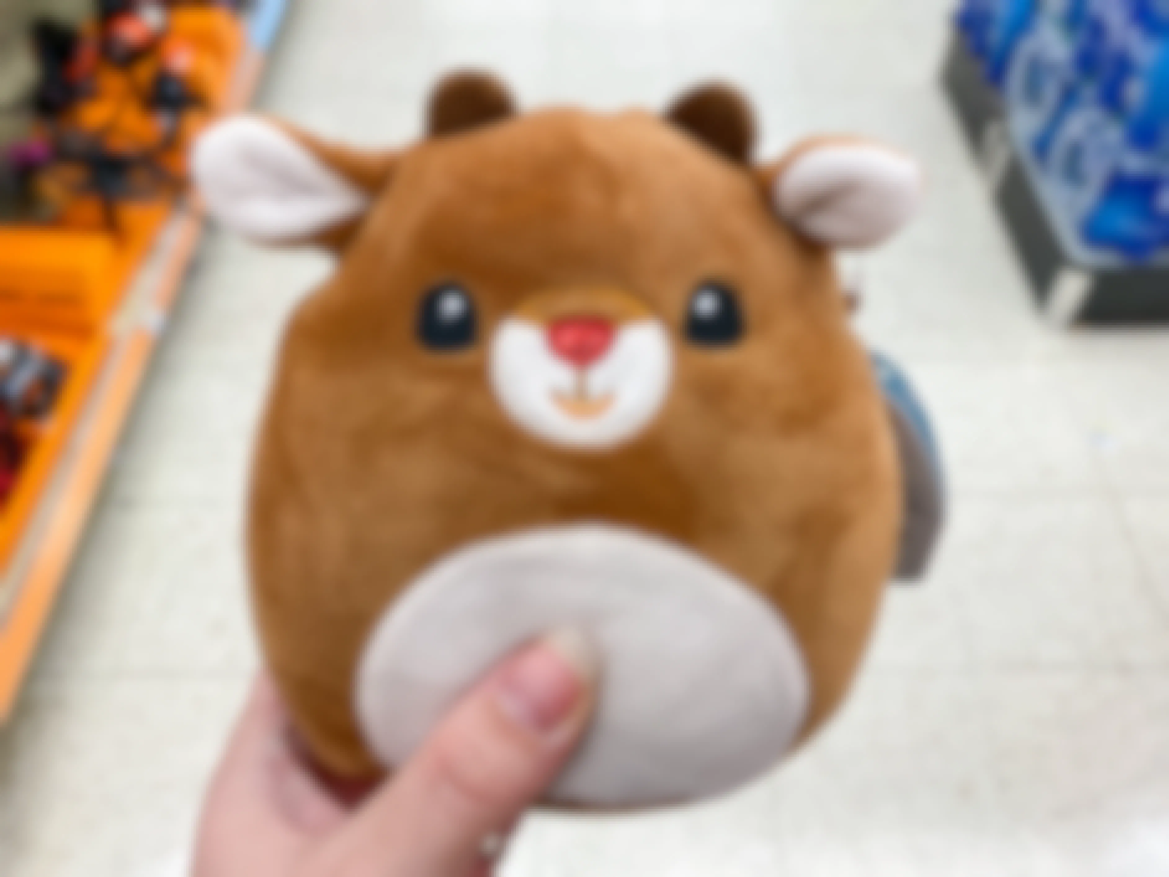 Someone holding a Rudolph holiday Squishmallow in an aisle at Walgreens.