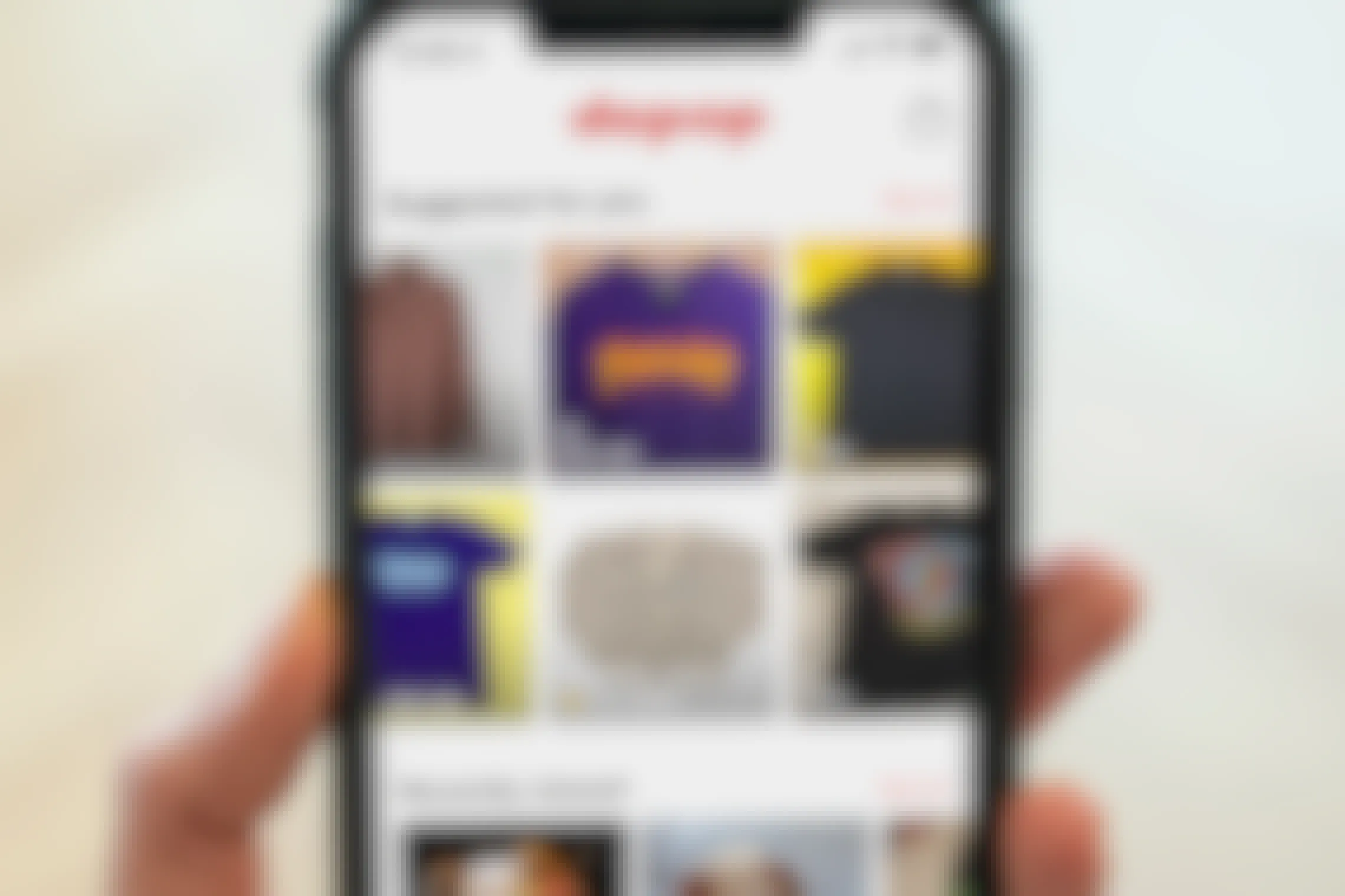 A hand holding up a cell phone displaying the Depop app.