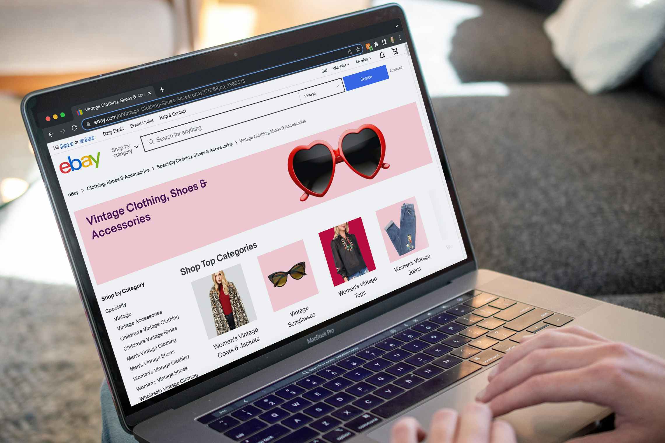 A person using a laptop displaying the vintage clothing page on eBay
