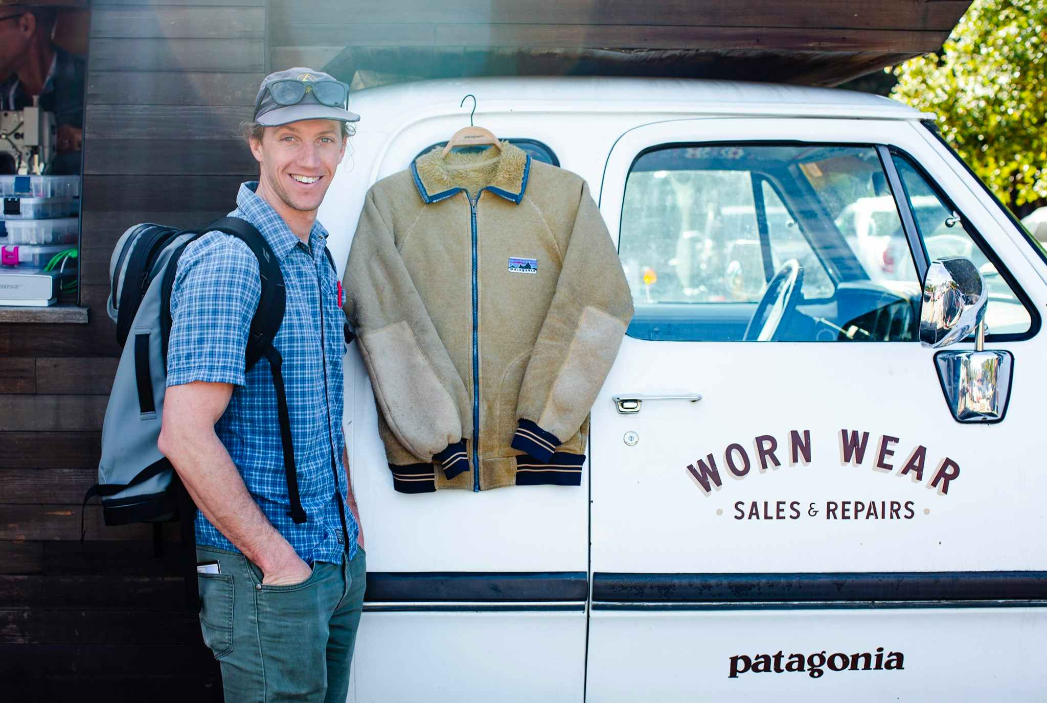 A man standing next to a Patagonia jacket hanging off of the Patagonia Worn Wear truck.