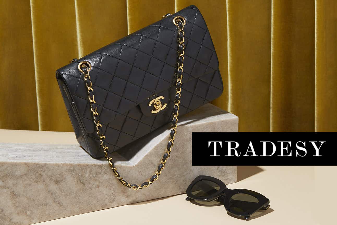 A hand bag and sunglasses on a display with the TRADESY logo in black and white.