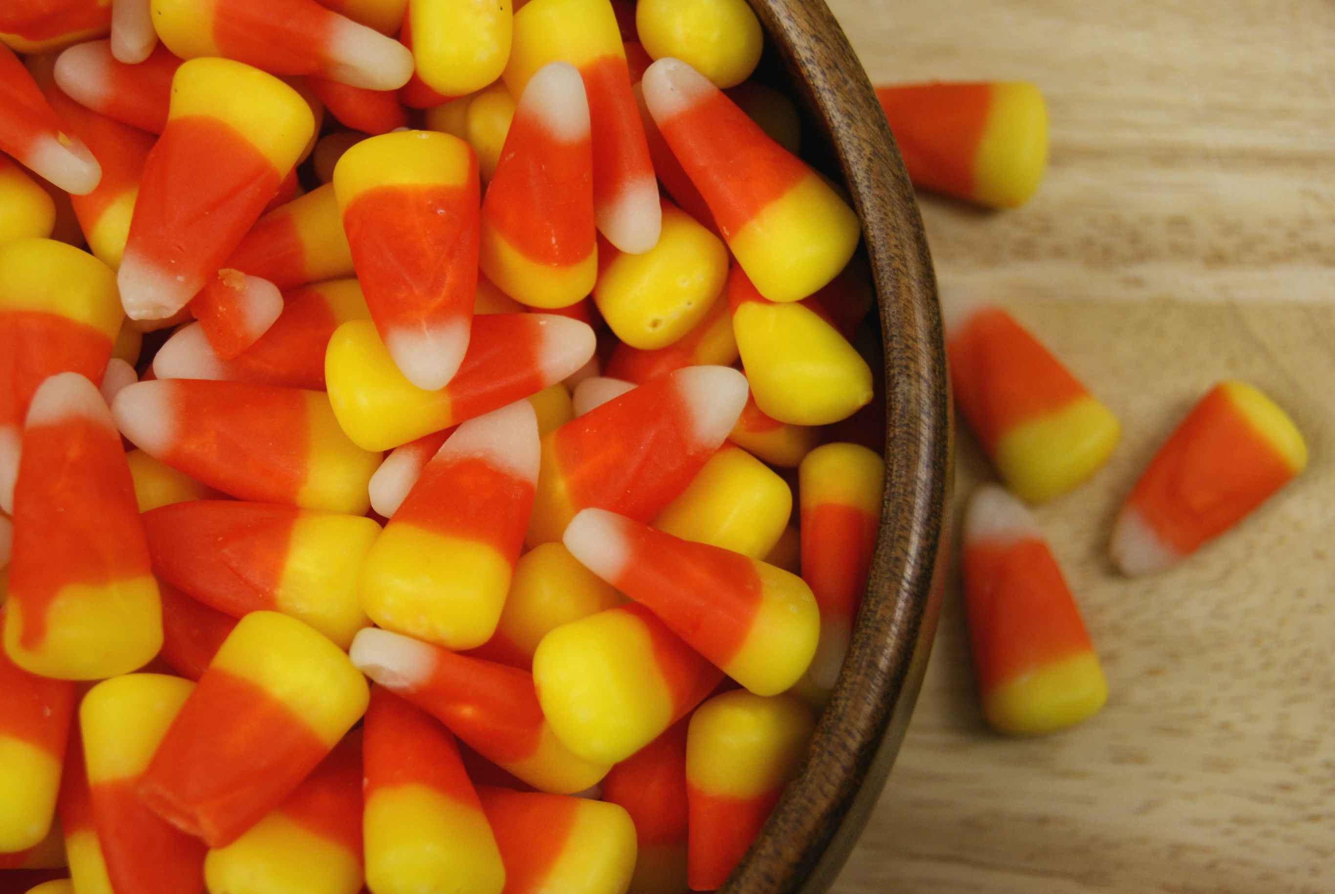 A close up on a bowl of candy corn sitting on a table.