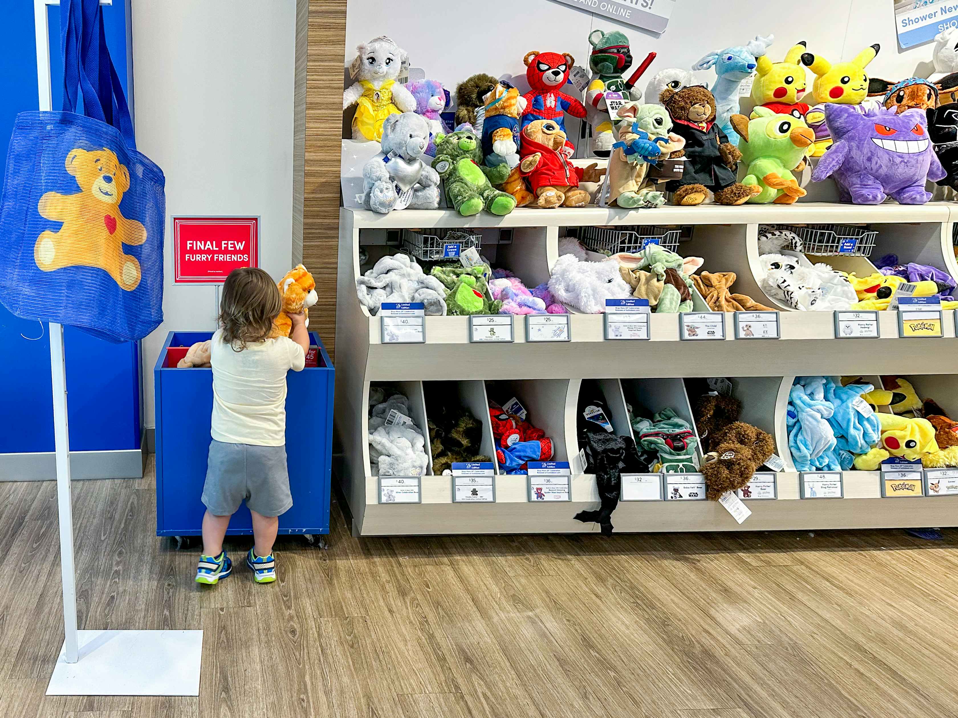 A little kid looking through some Build-A-Bear options on the shelf