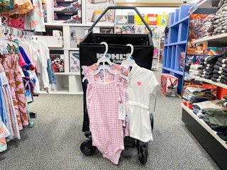 Carter's children's outfits hanging from Kohls shopping cart.