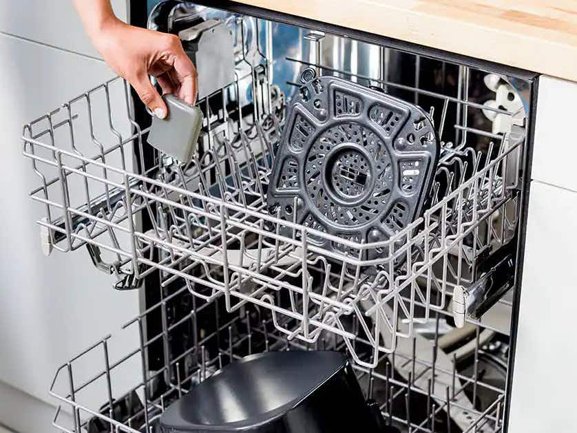 person putting ninja air fryer crisper tray and accessories in dishwasher