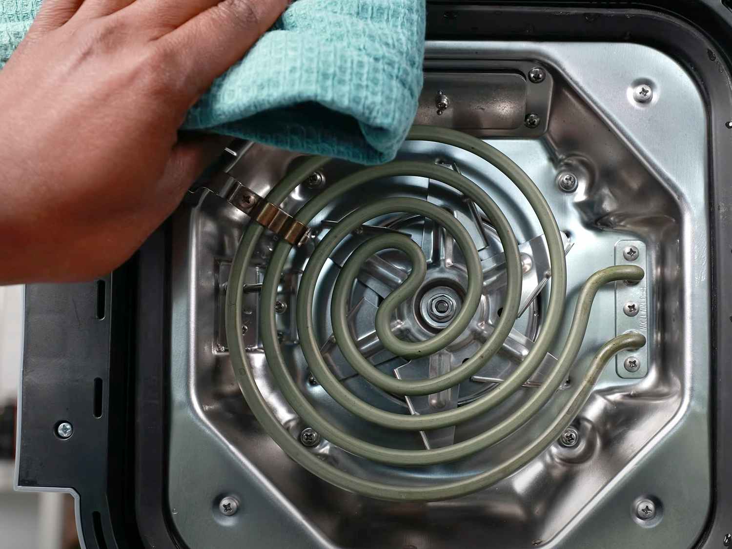 person wiping ninja air fryer heating element with cloth