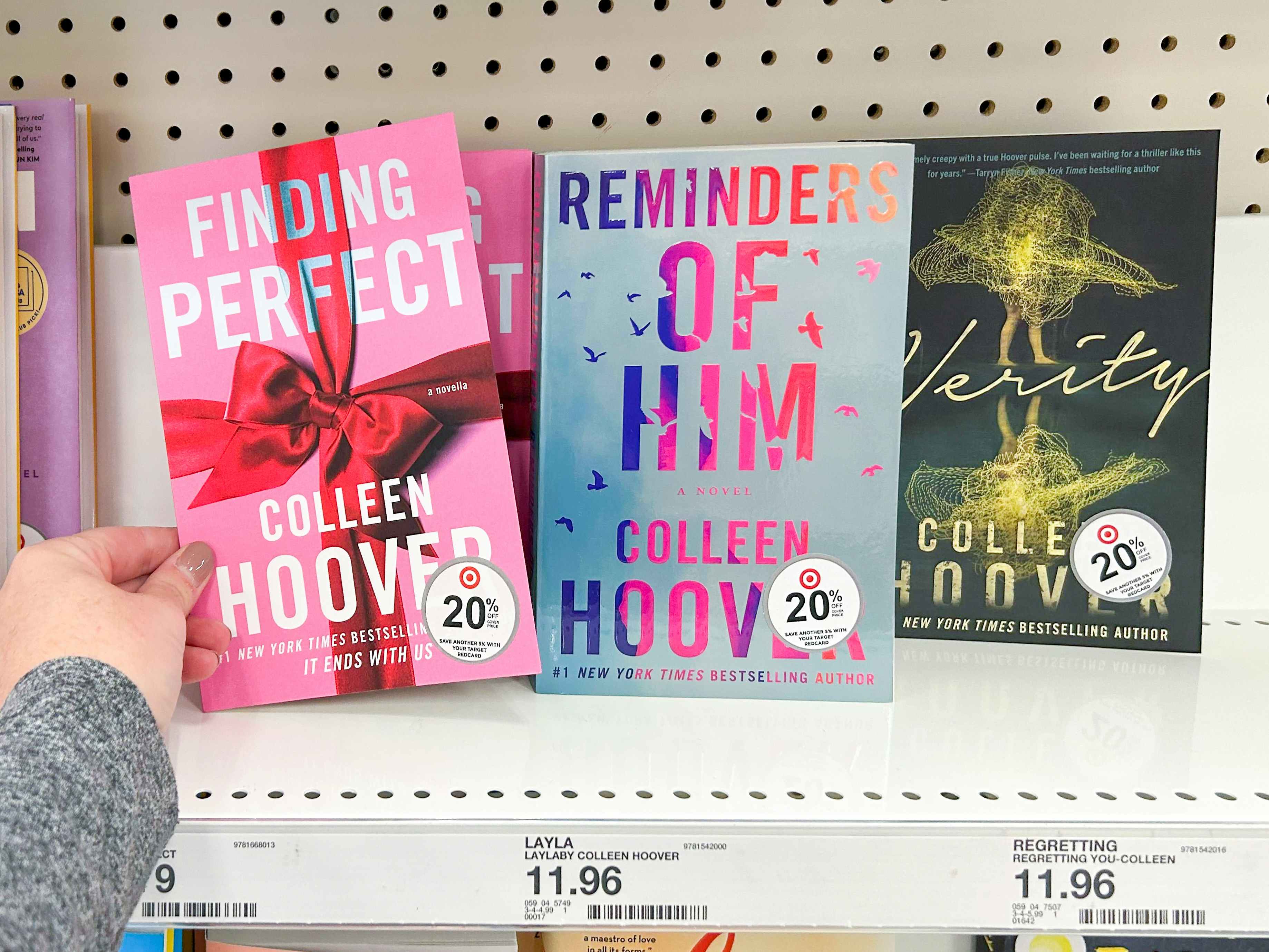 A person taking a Colleen Hoover book from a shelf at Target