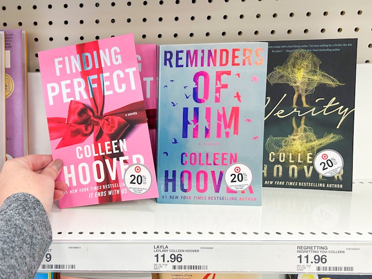 A person taking a Colleen Hoover book from a shelf at Target