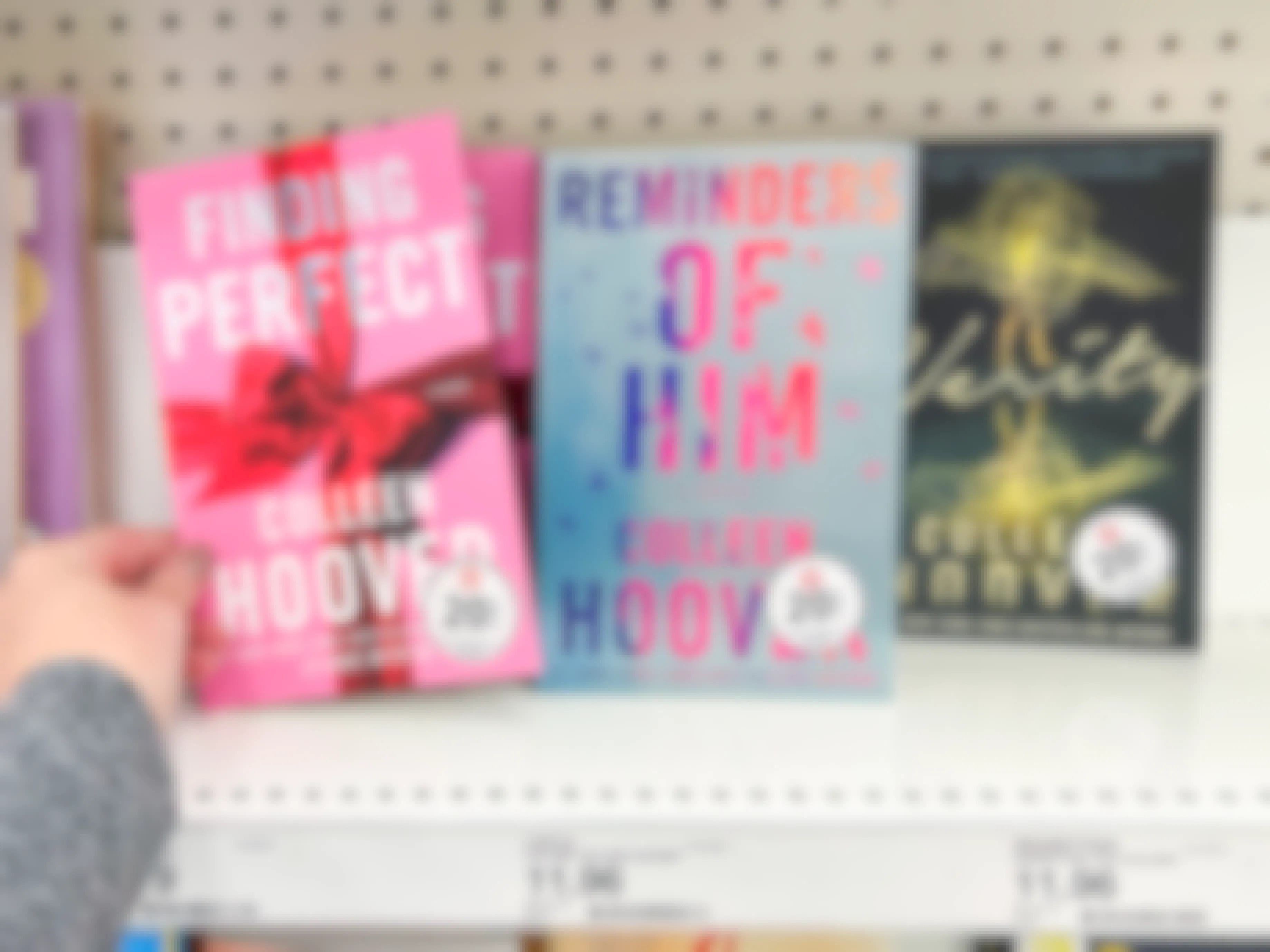 A person taking a Colleen Hoover book from a shelf at Target