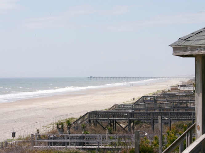 beach and ocean with beach house stairs lining the beachfront 