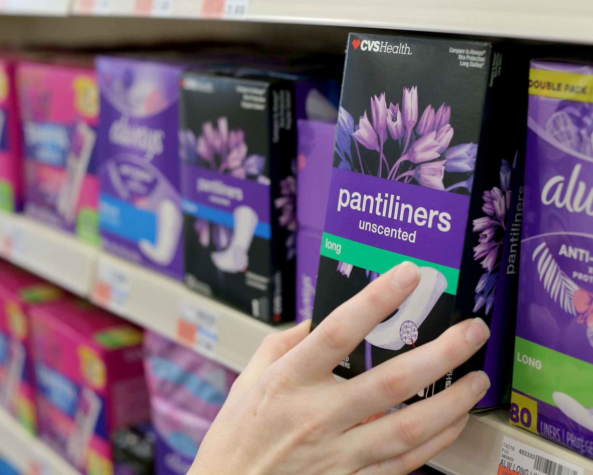 hand grabbing cvs brand pantiliners from shelf in store