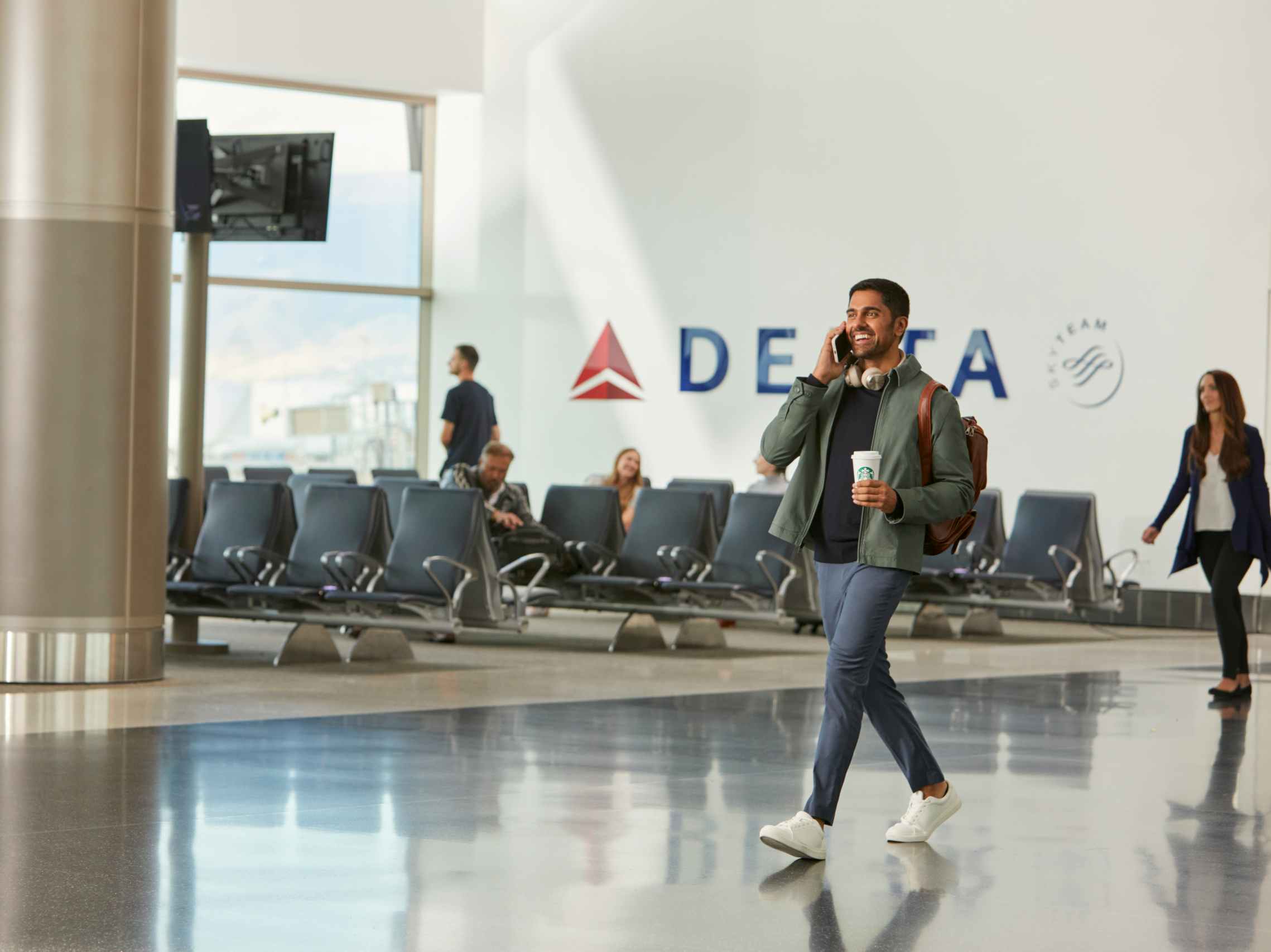 a man walking past a Delta gate in the airport