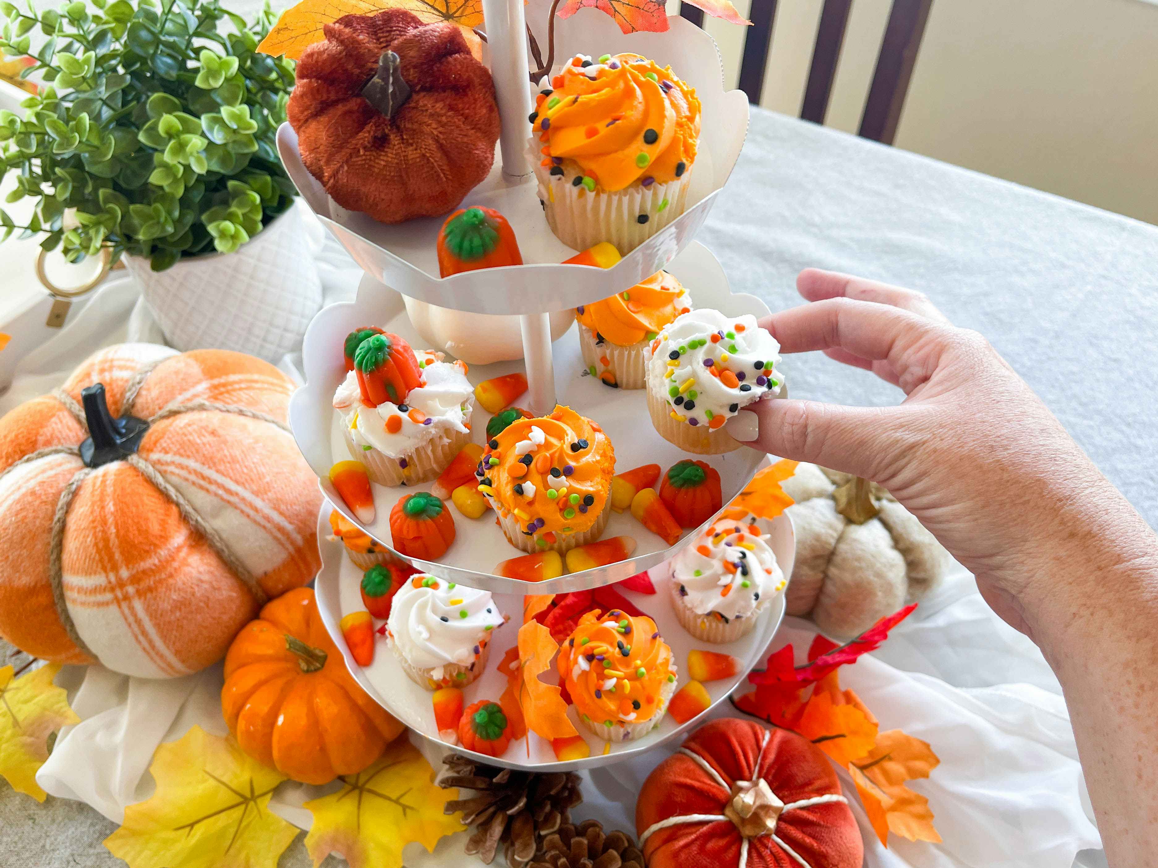 a tiered tray of fall themed cupcakes 