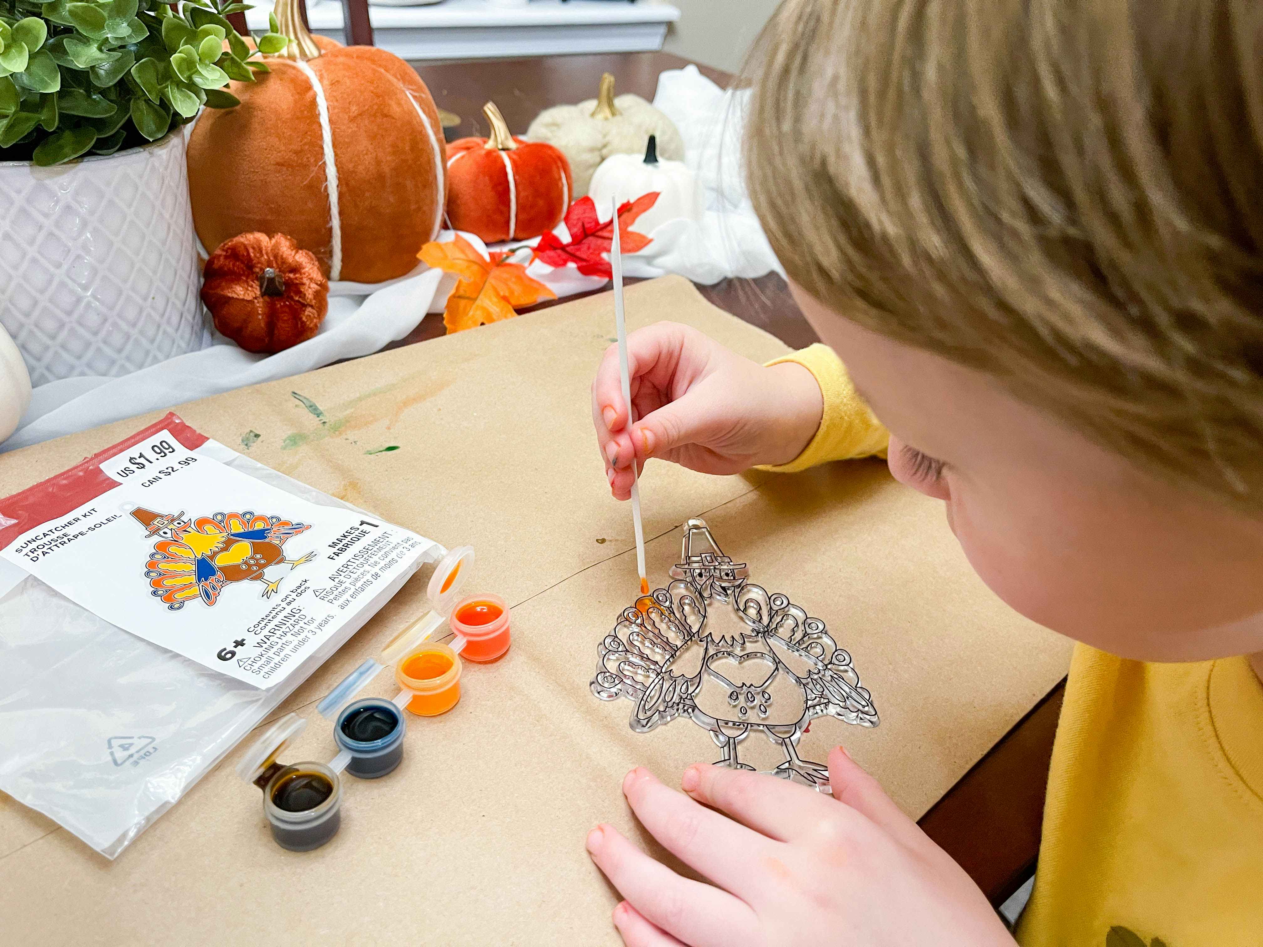 a young child painting a thanksgiving michaels suncatcher crafts