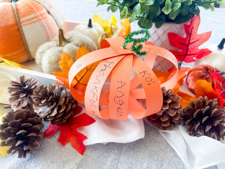 a diy thanksgiving pumpkin out of strips of construction paper with names on it