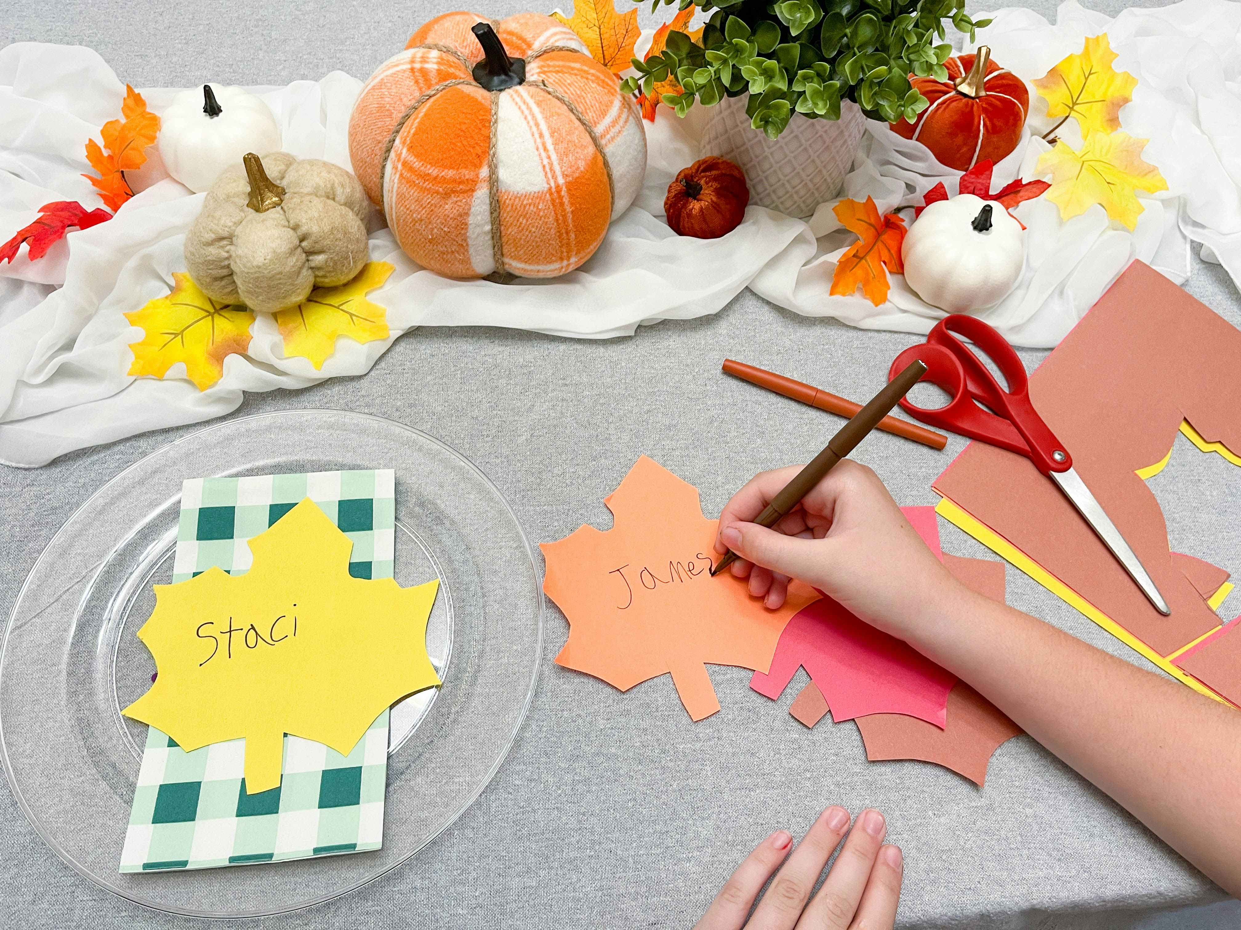 a child writing names on diy cut construction leaves.