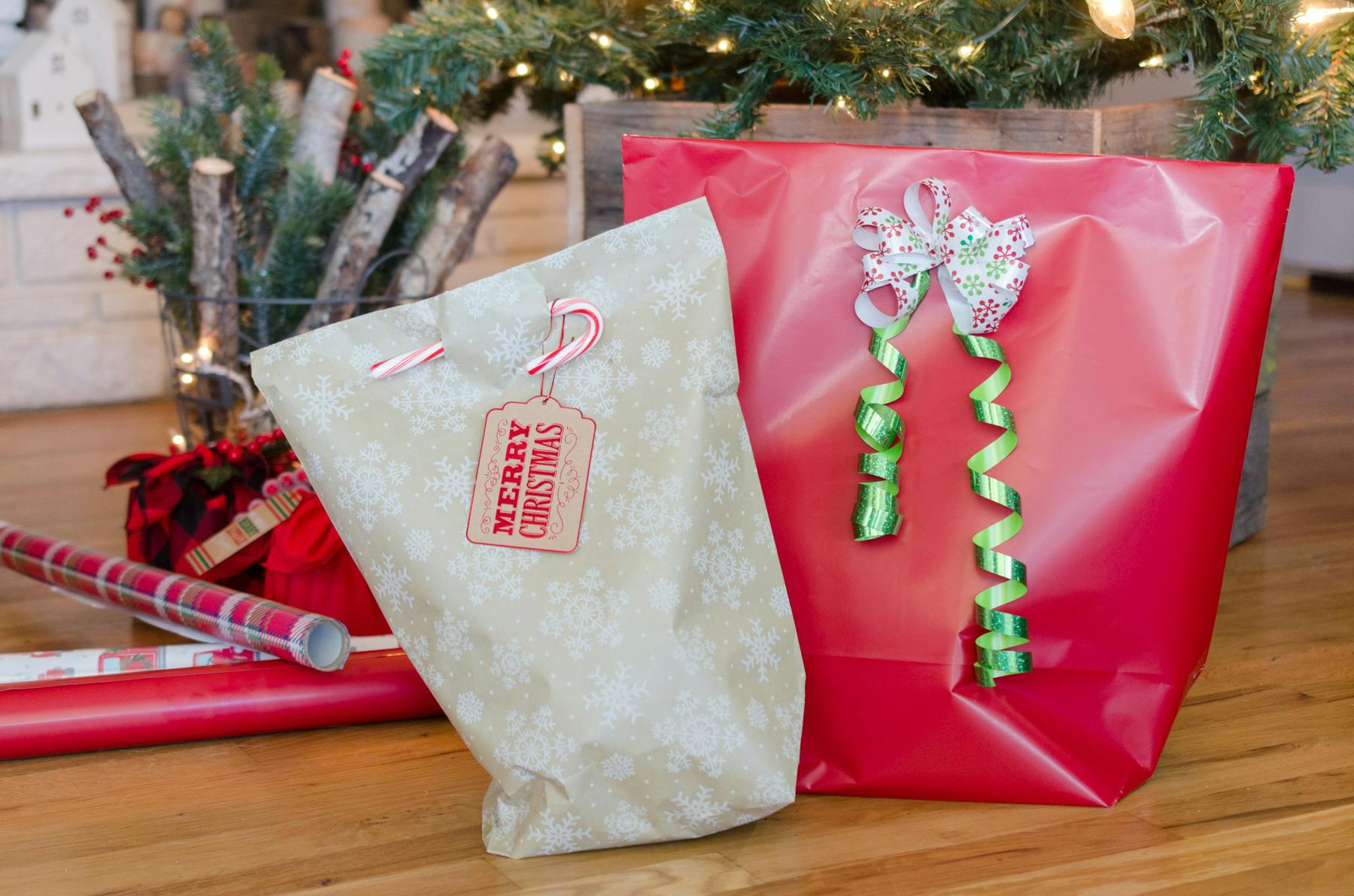 two diy wrapping paper bags sitting near a christmas tree with gift wrap near by.