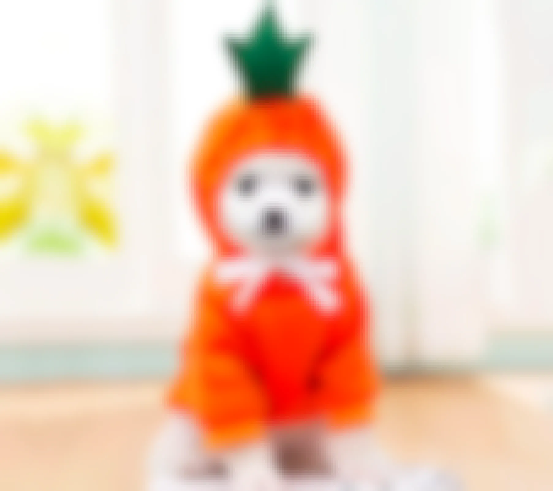 A dog wearing an orange hoodie with a green sprig on top of its head 