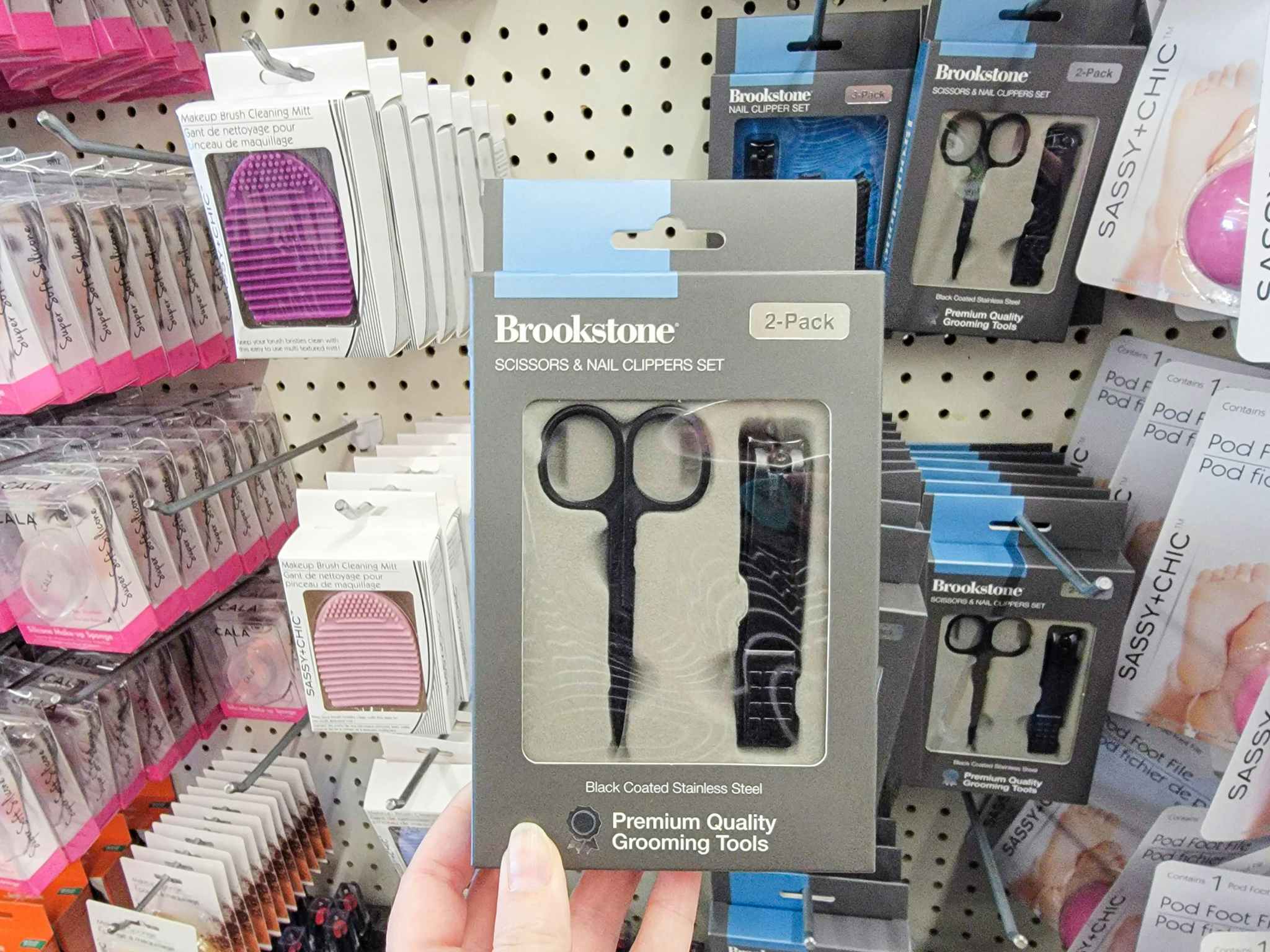 hand holding a brookstone grooming kit with nail clippers and scissors