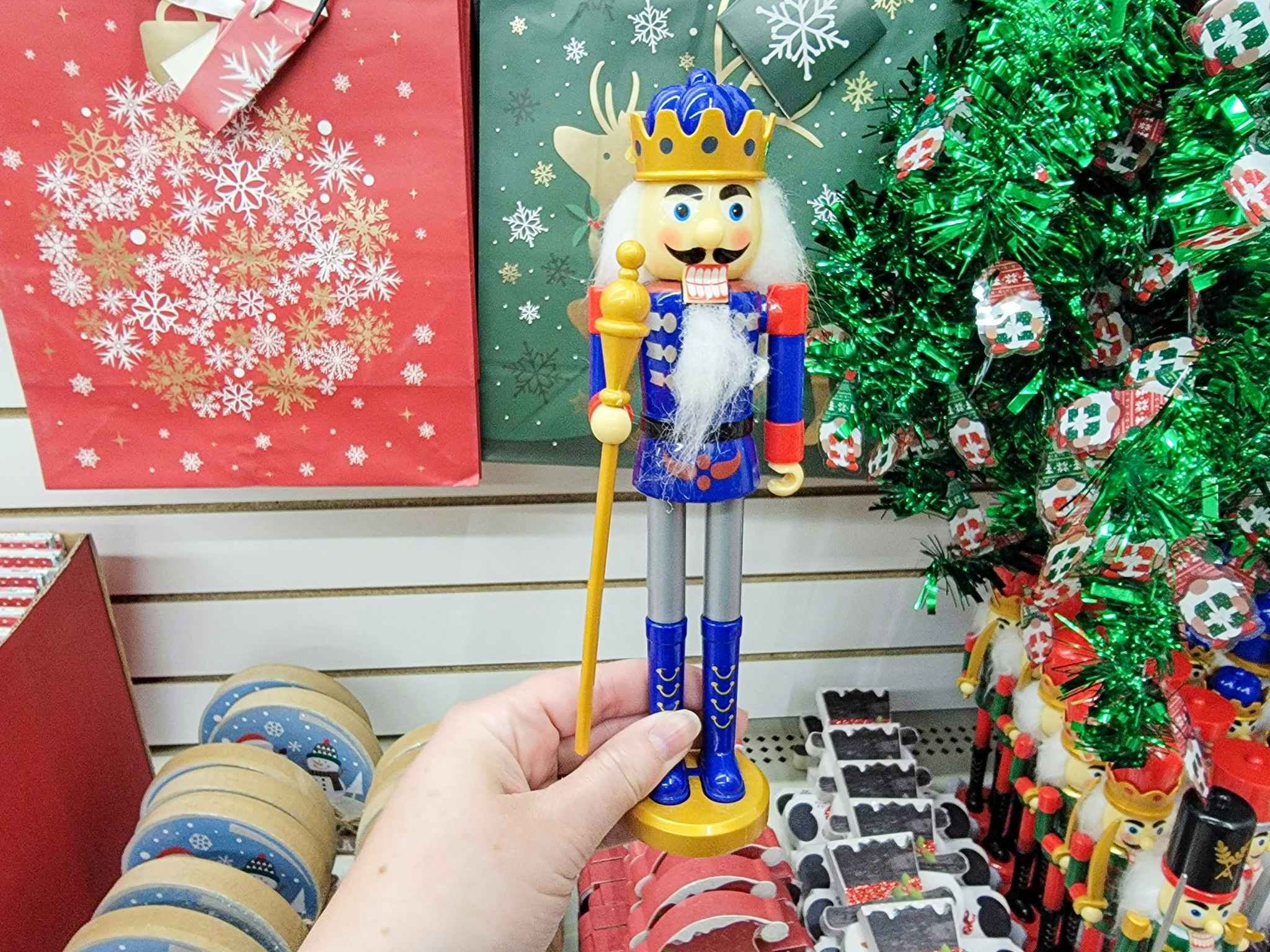 hand holding a nutcracker in a blue jacket