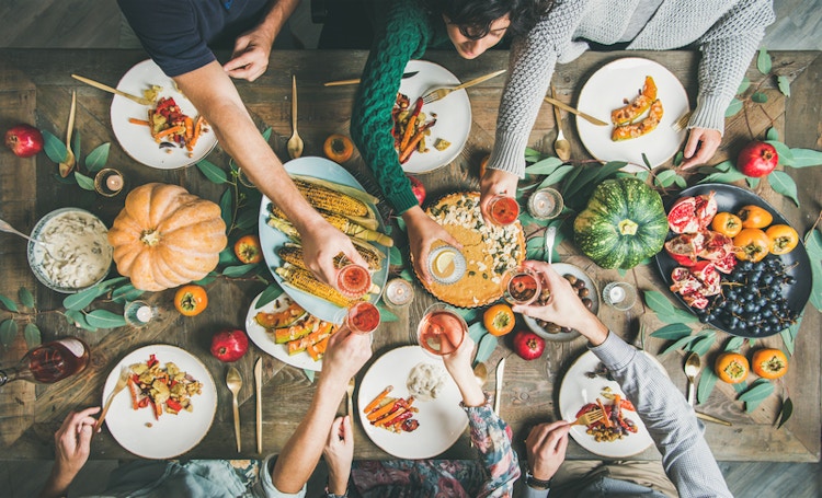 a table full of thanksgiving dinner with friends cheering glasses