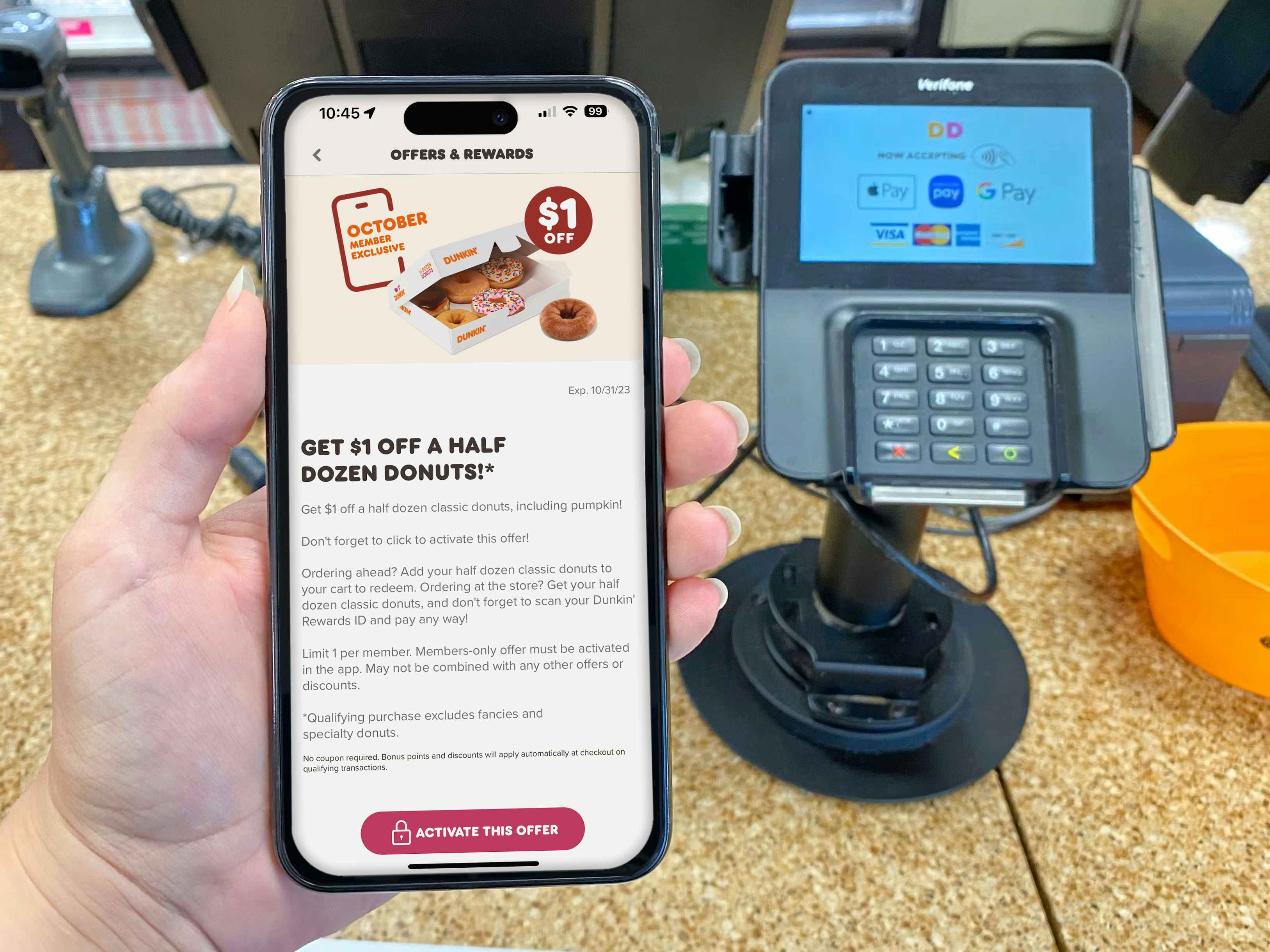 someone holding a phone at the dunkin counter displaying an offer for October